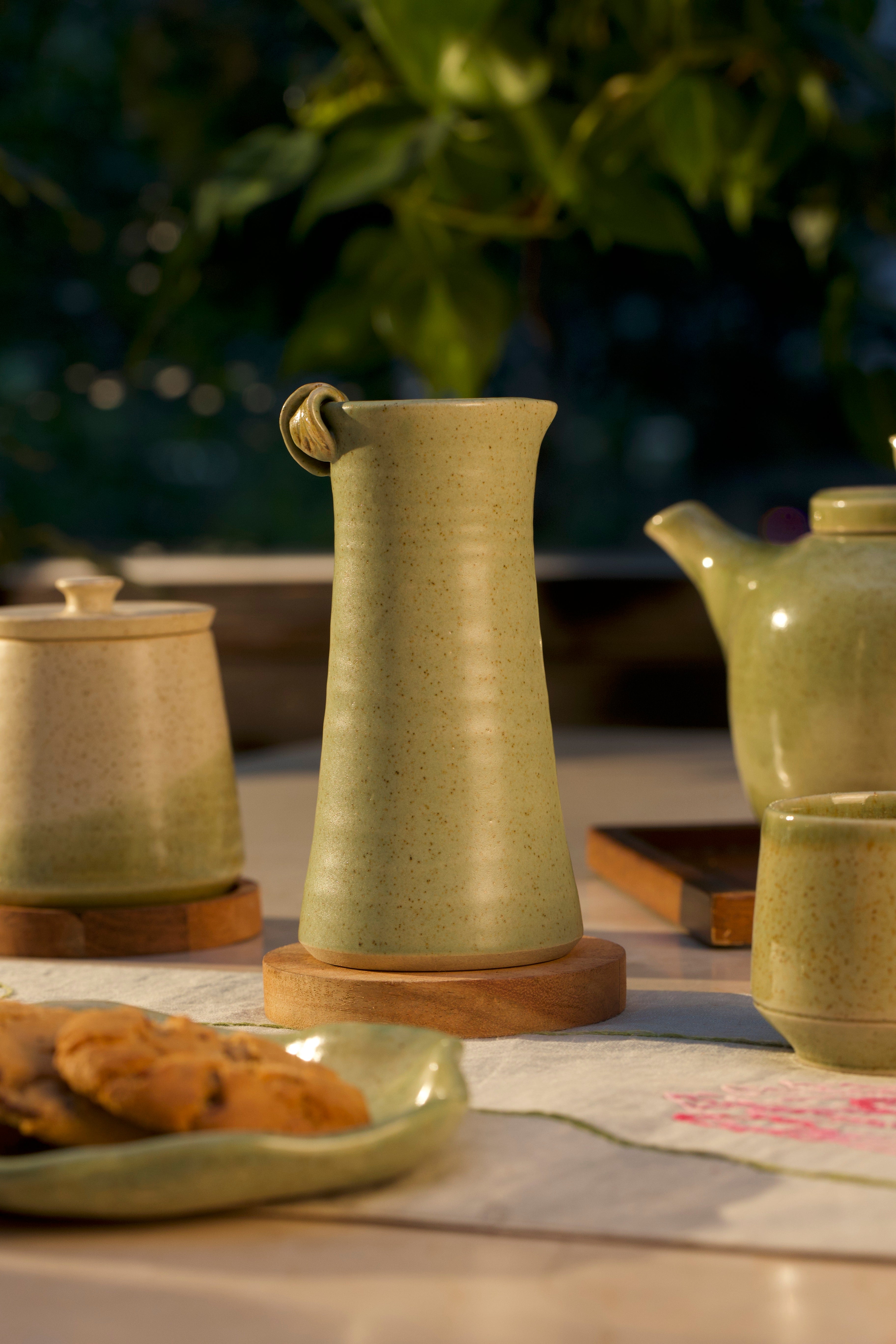 Green ceramic teapot and other teaware on a table, ceramic tableware India, pottery brands in India
