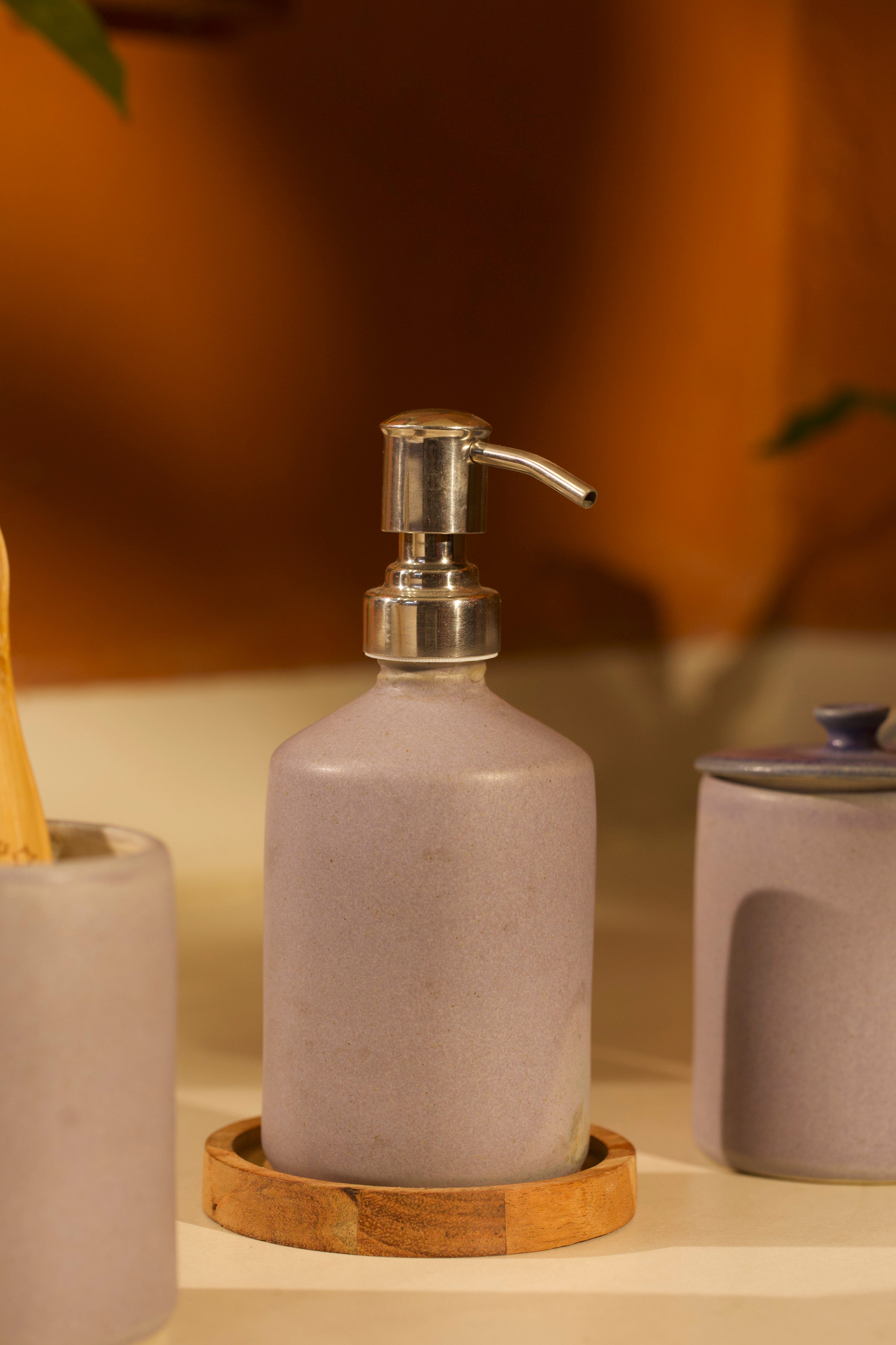 Pink ceramic soap dispenser with pump on a wooden tray, ceramic home décor online, pottery home decor