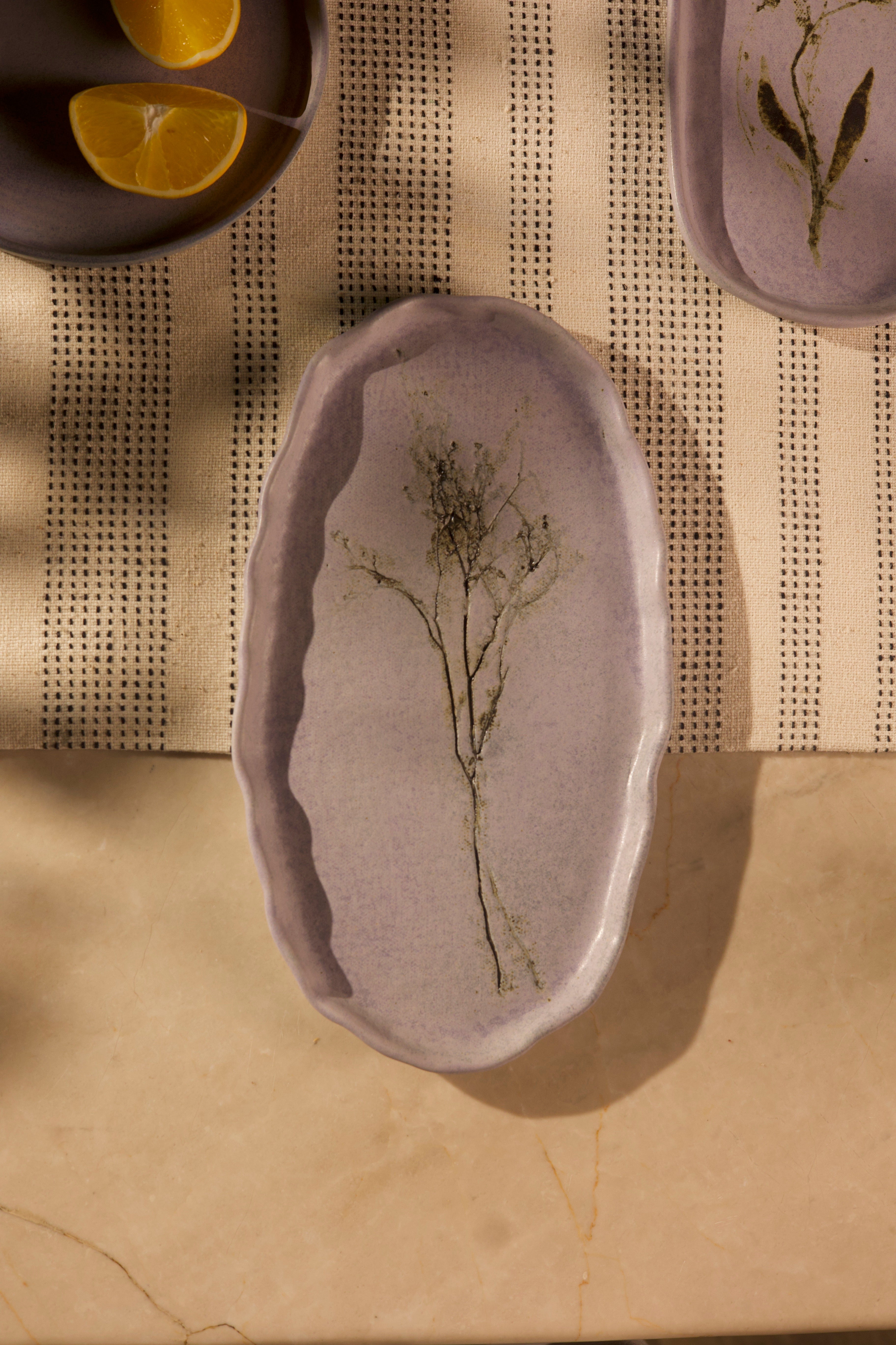 A pink ceramic dish with plant design on a textured surface, handcrafted plates and bowls, dinner plates with natural glaze