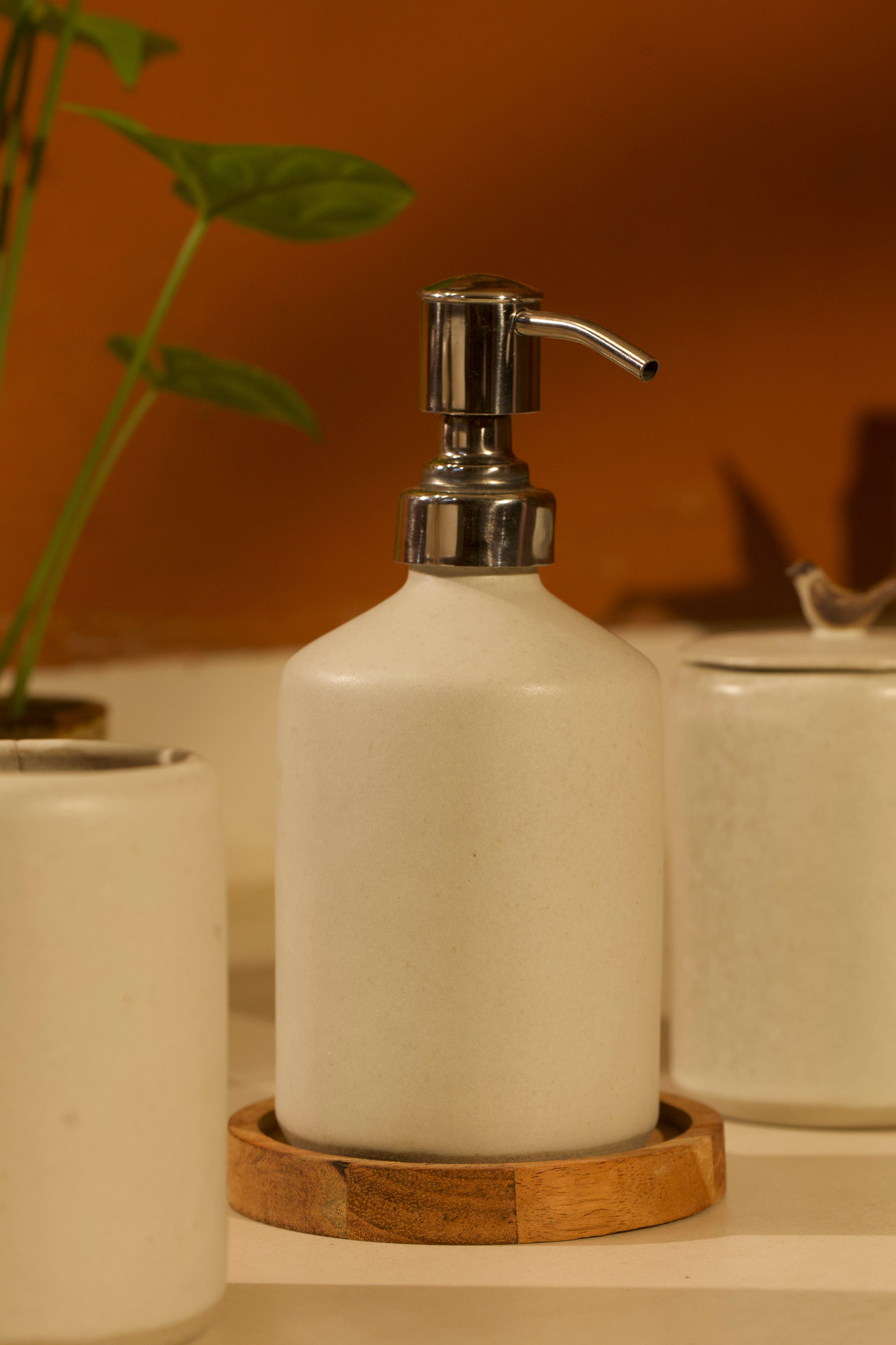 White ceramic soap dispenser with silver pump on a wooden coaster. ceramic home décor online, pottery home decor