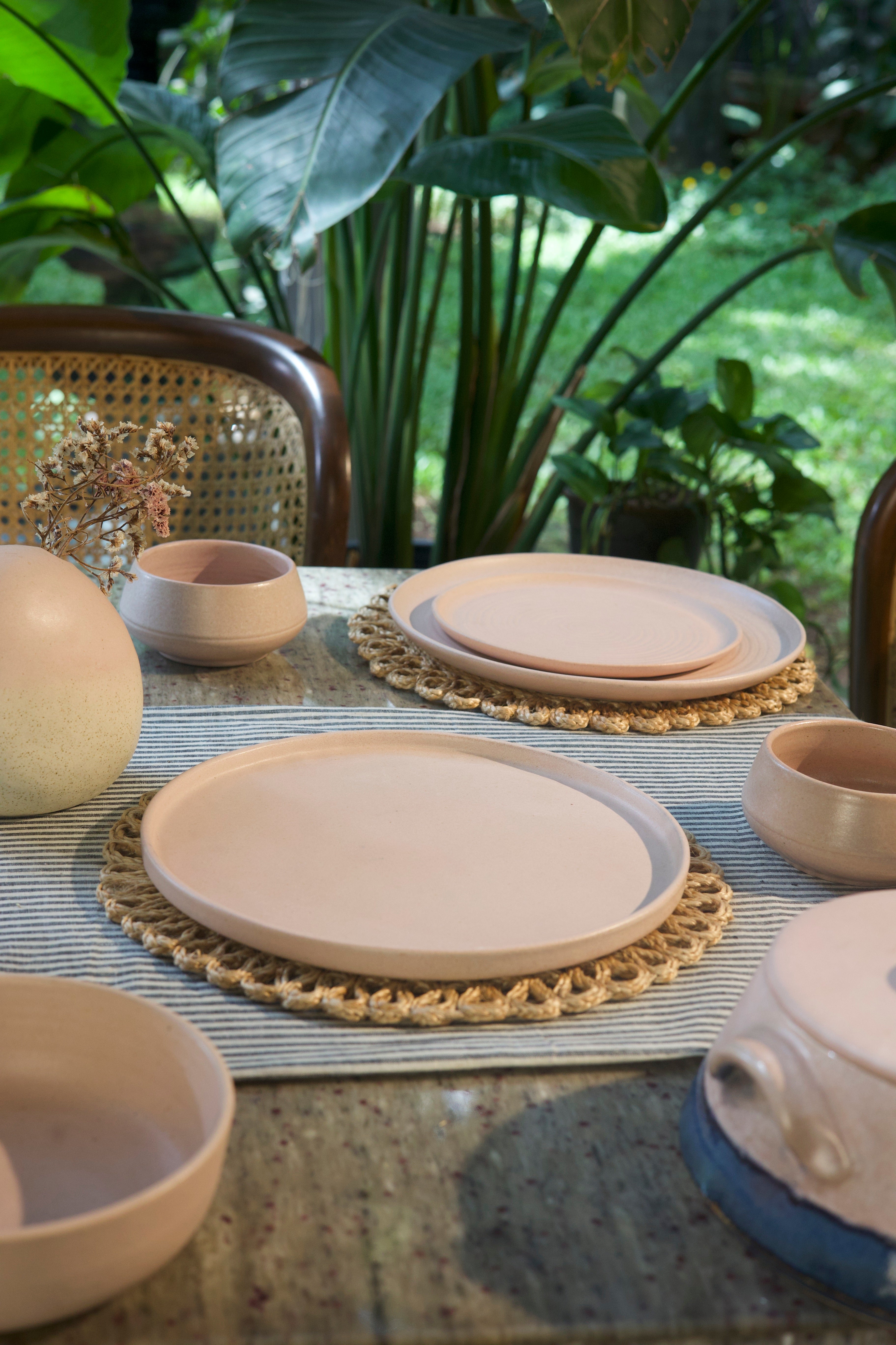 Pink ceramic plates and bowls on a table with a natural background, handmade dinnerware India, handcrafted plates and bowls