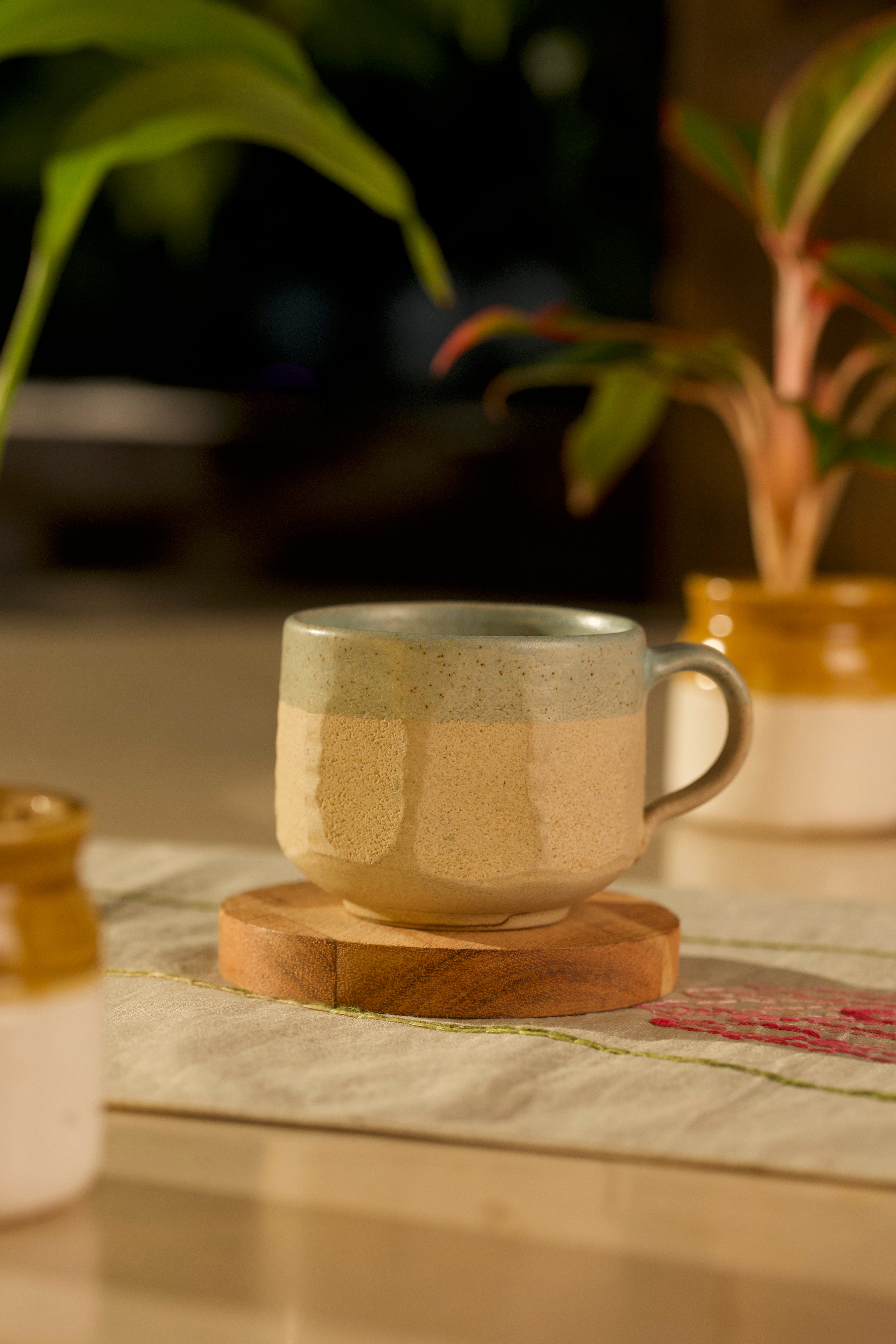 Ceramic mug on a wooden coaster with plants in the background handmade tea sets India, handmade serving bowls IndiaTea