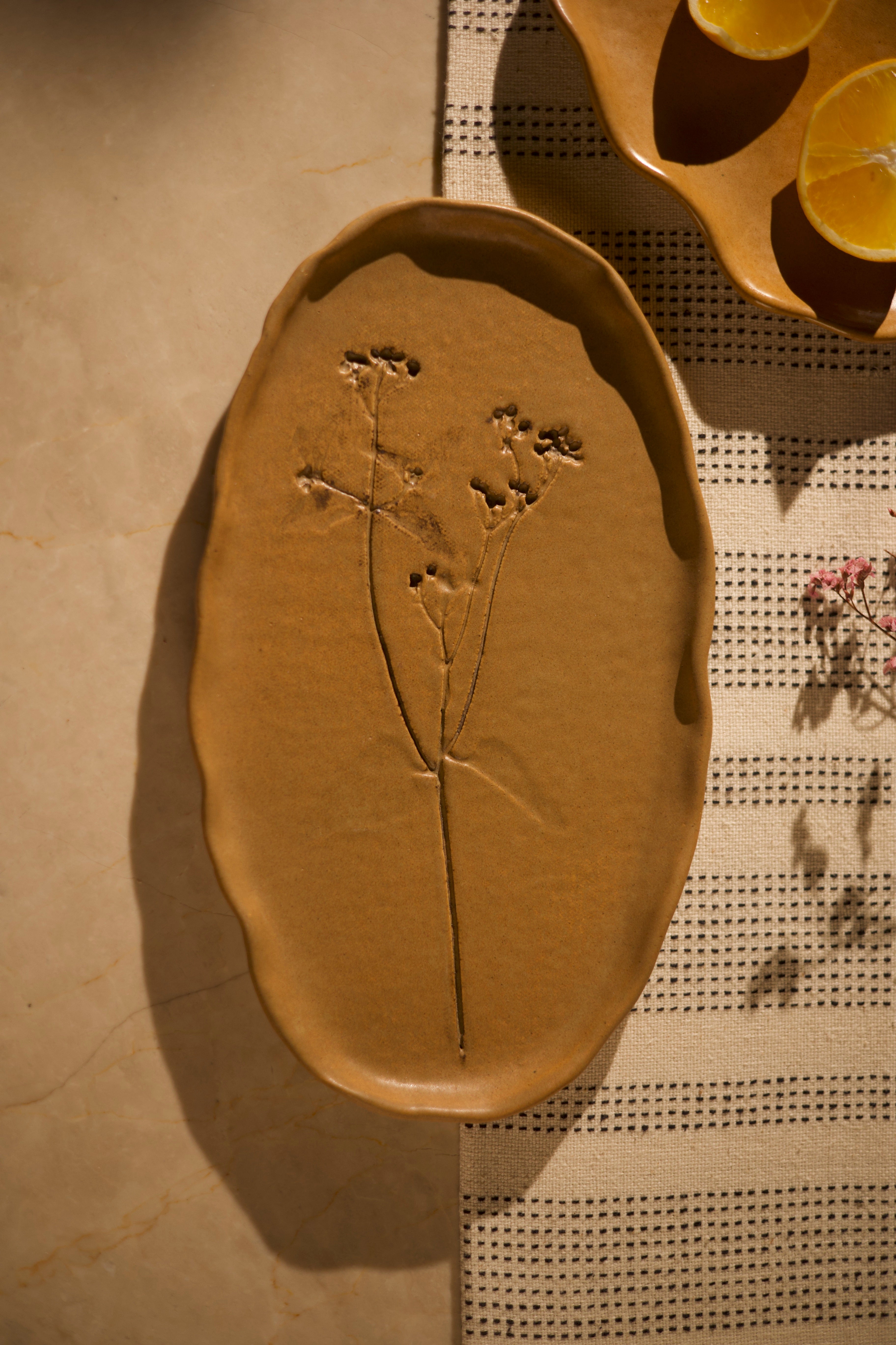 Mustard ceramic dish with embossed plant design on a textured surface, handcrafted plates and bowls, dinner plates with natural glaze