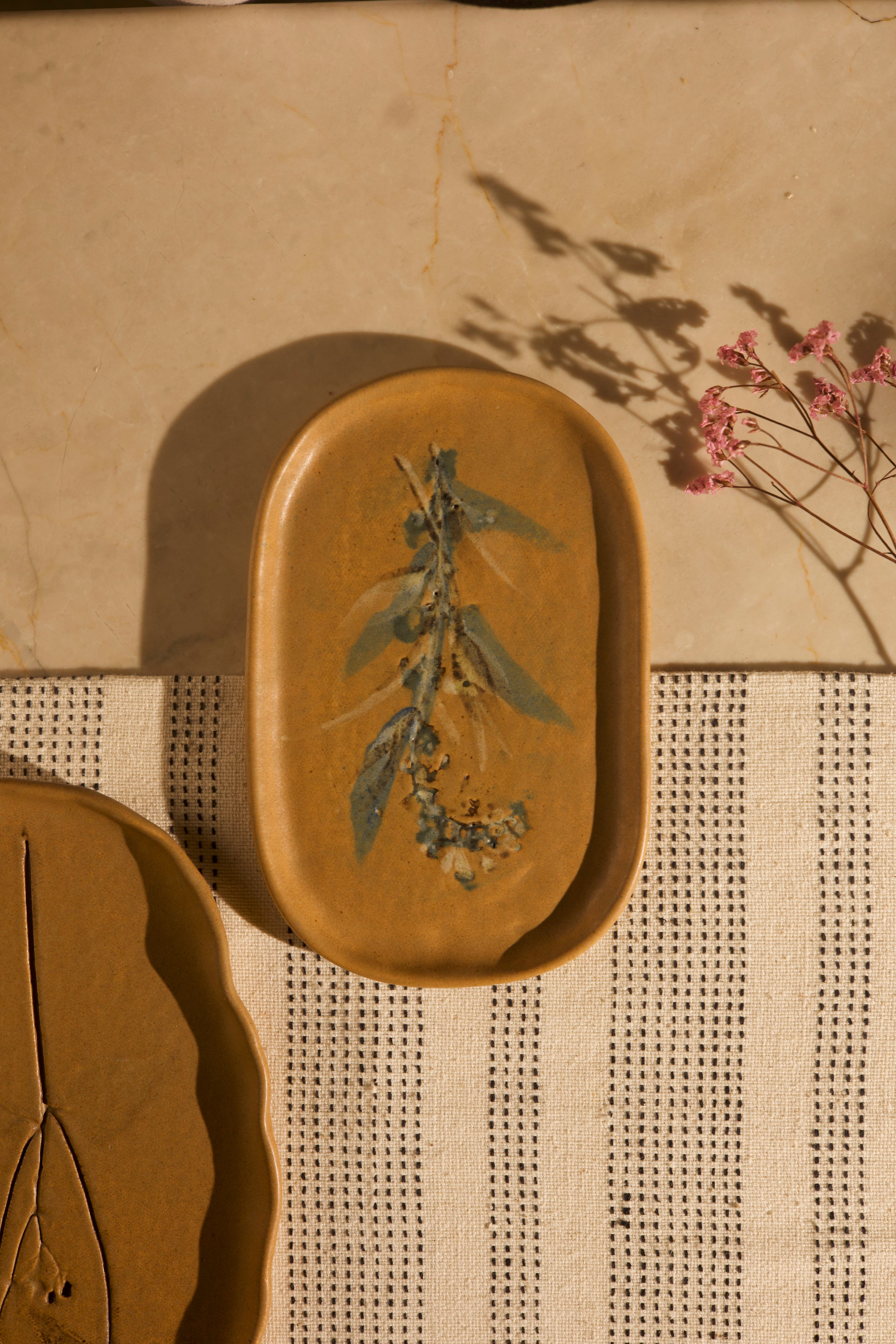 Mustard ceramic dish with floral design on a textured surface, handcrafted plates and bowls, dinner plates with natural glaze