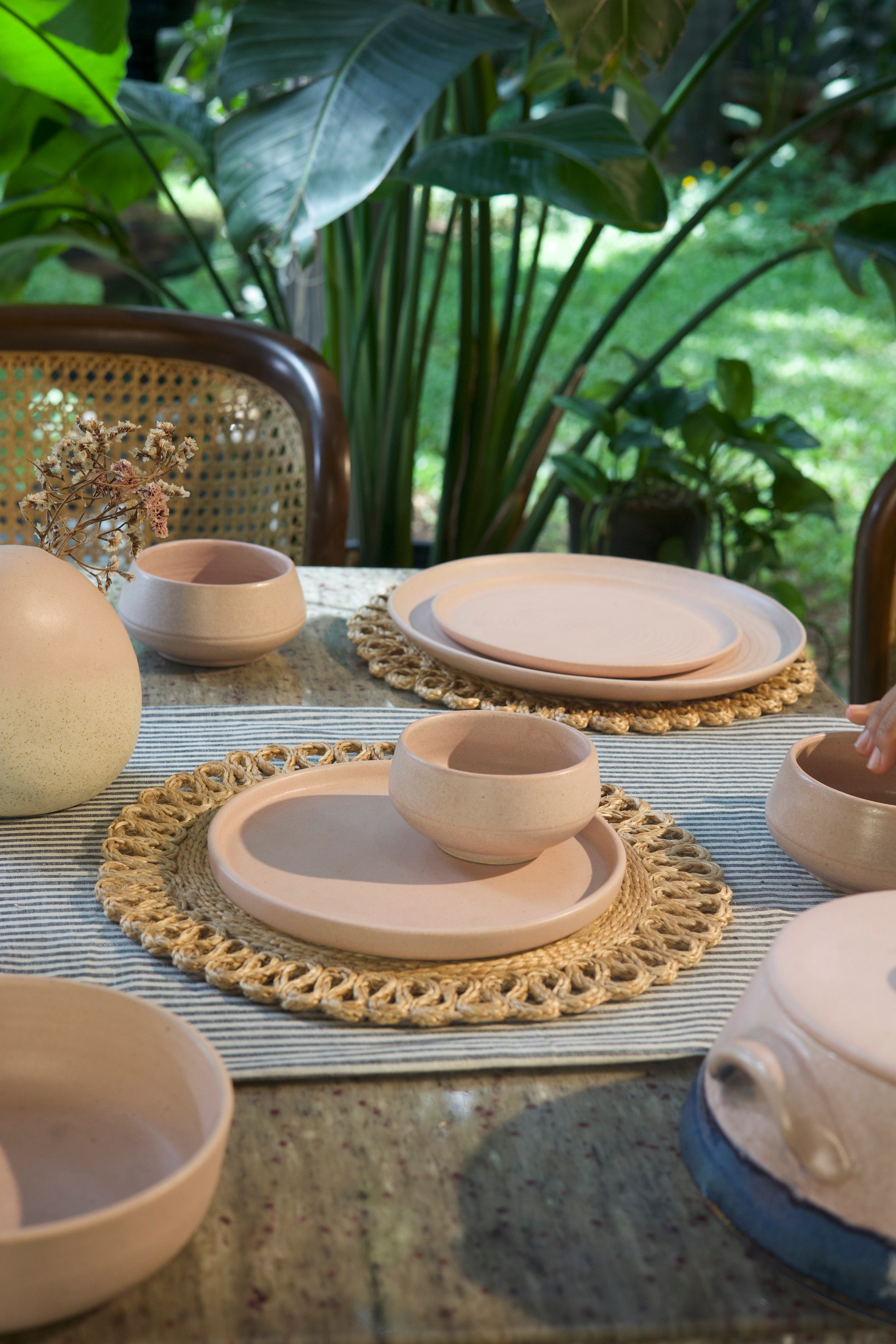 Set of ceramic plates and bowls on a table with a natural background, handmade dinnerware India, handcrafted plates and bowls