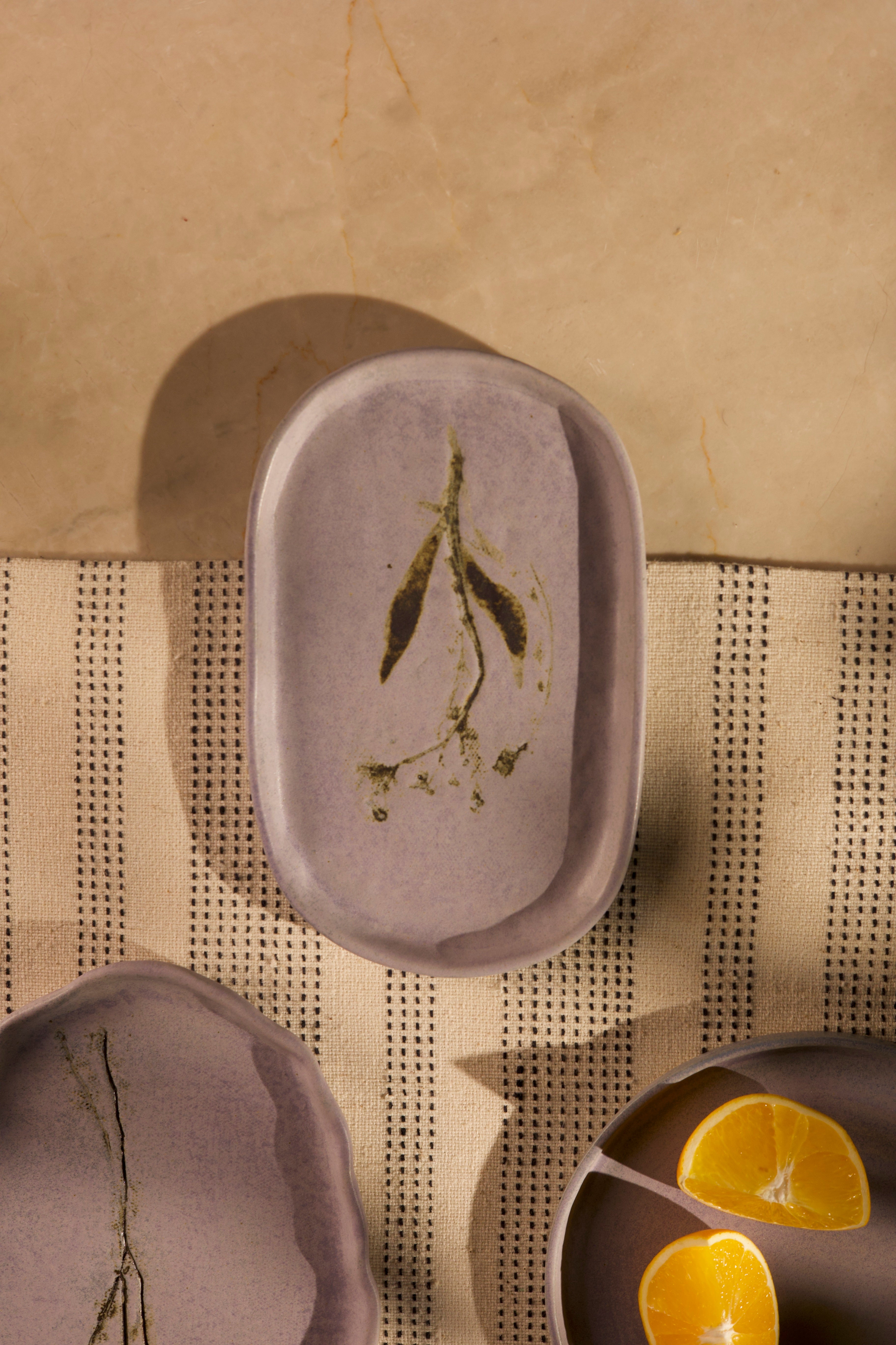 Pink ceramic dish with green leaves on a textured surface, handcrafted plates and bowls, dinner plates with natural glaze