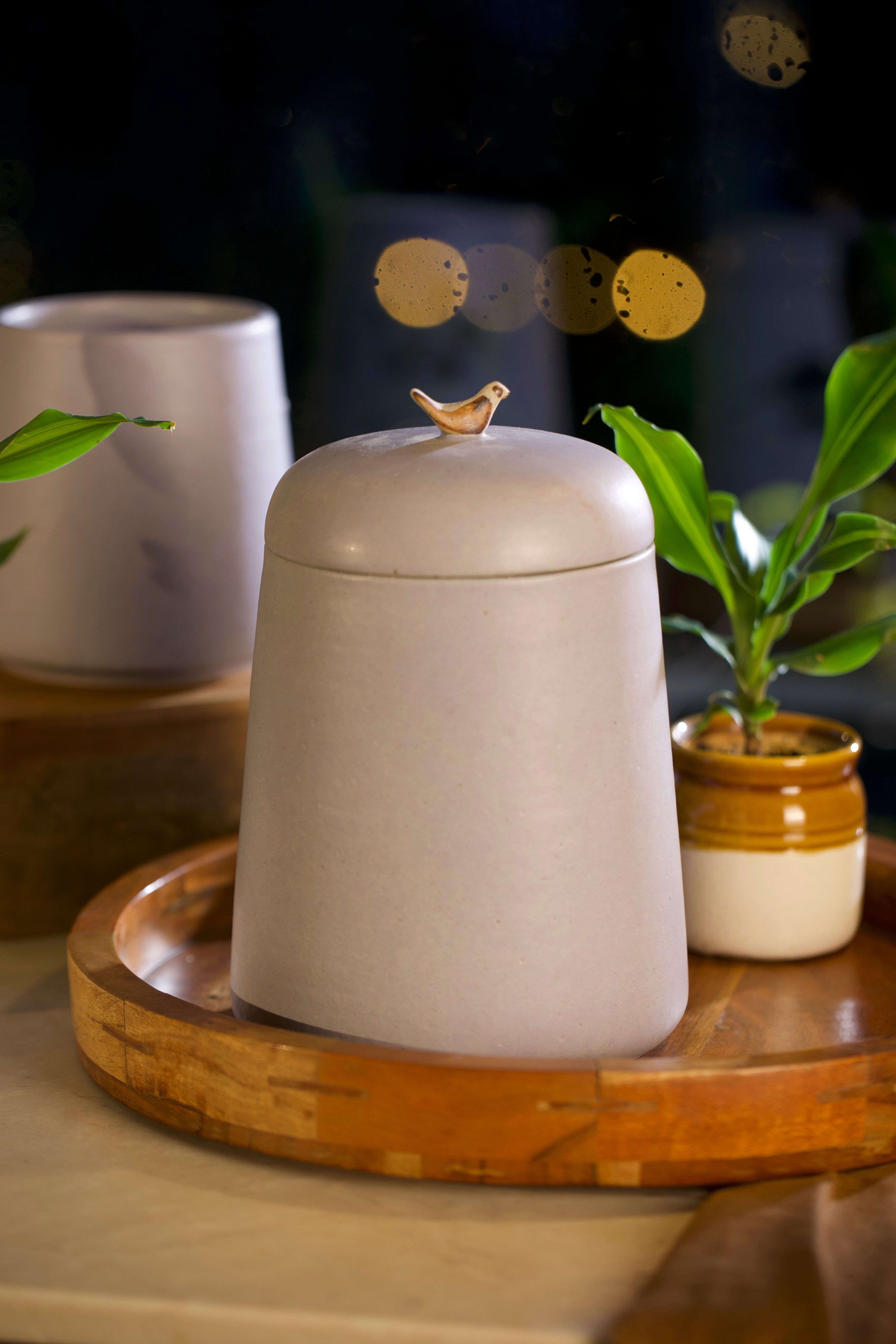 White ceramic jar with a gold bird on top, placed on a wooden tray pottery home decor, handmade serveware online