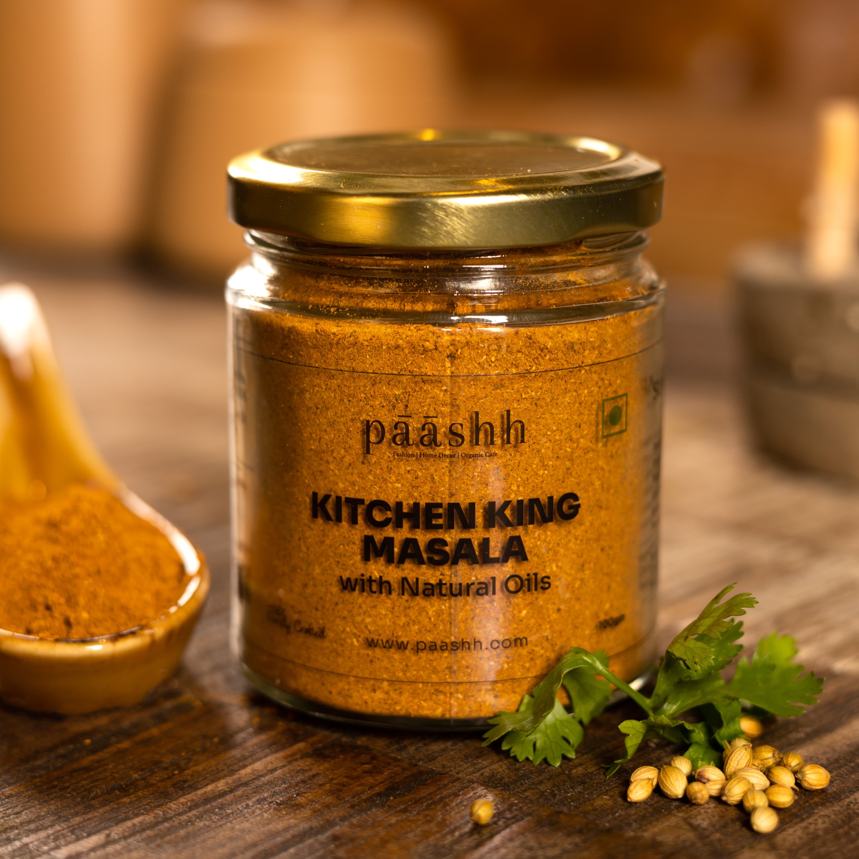 Jar of paashh Kitchen King Masala on a wooden surface with spices and herbs. handcrafted masala blends India, organic kitchen ingredients