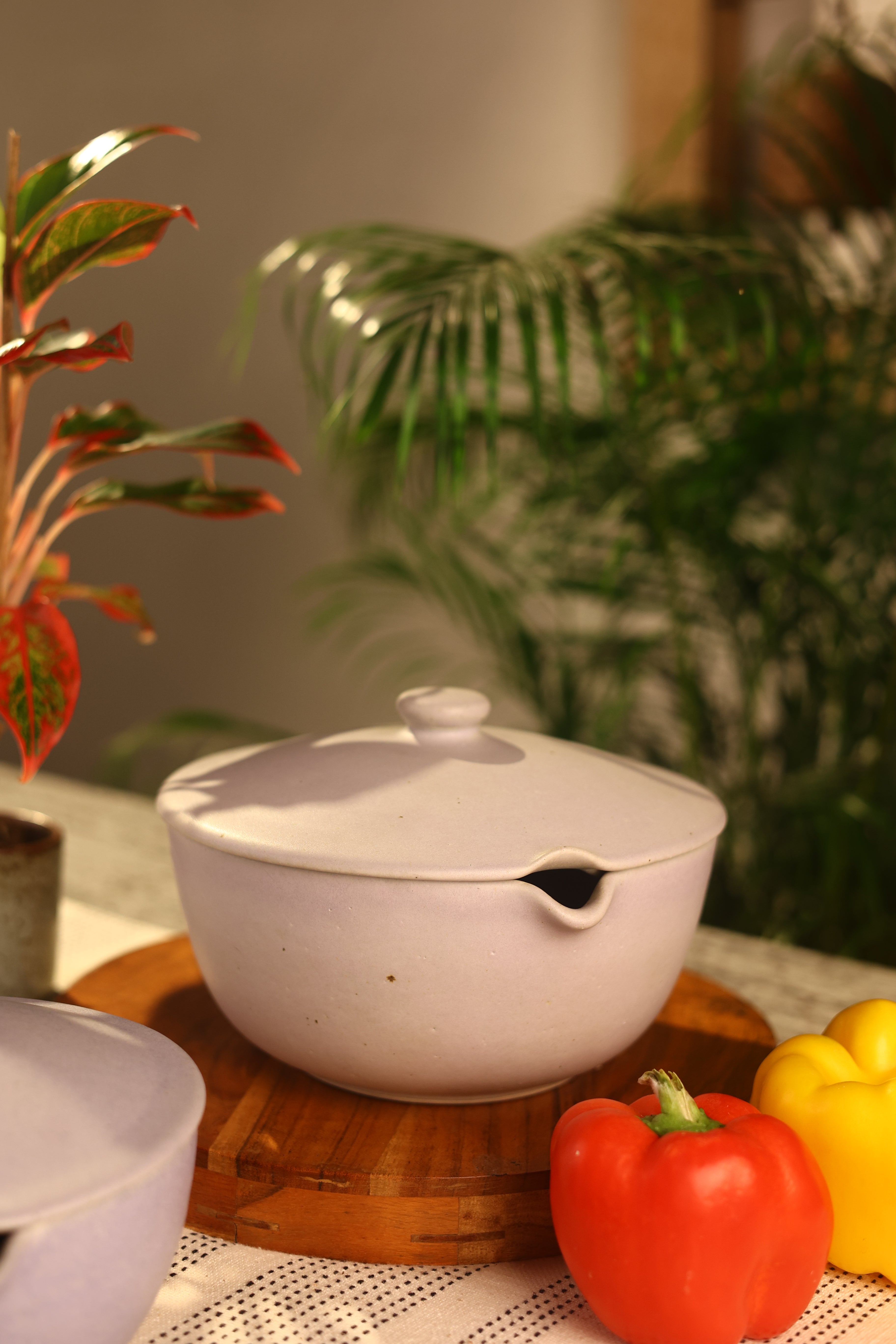 A pink ceramic pot with a lid on a wooden surface artisanal serveware India, handcrafted plates and bowls