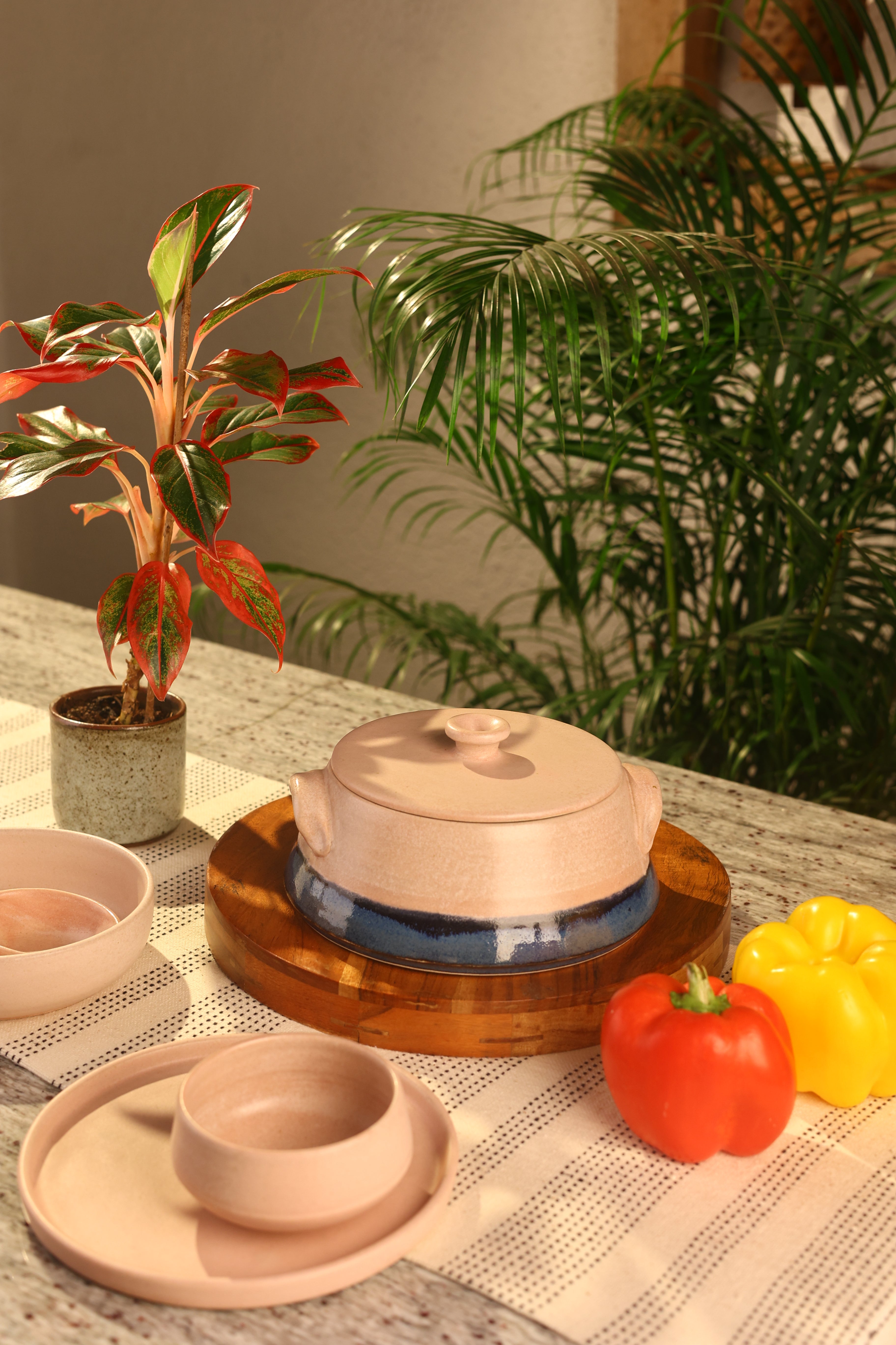A pink ceramic pot with a lid on a wooden surface artisanal serveware India, 
handcrafted plates and bowls