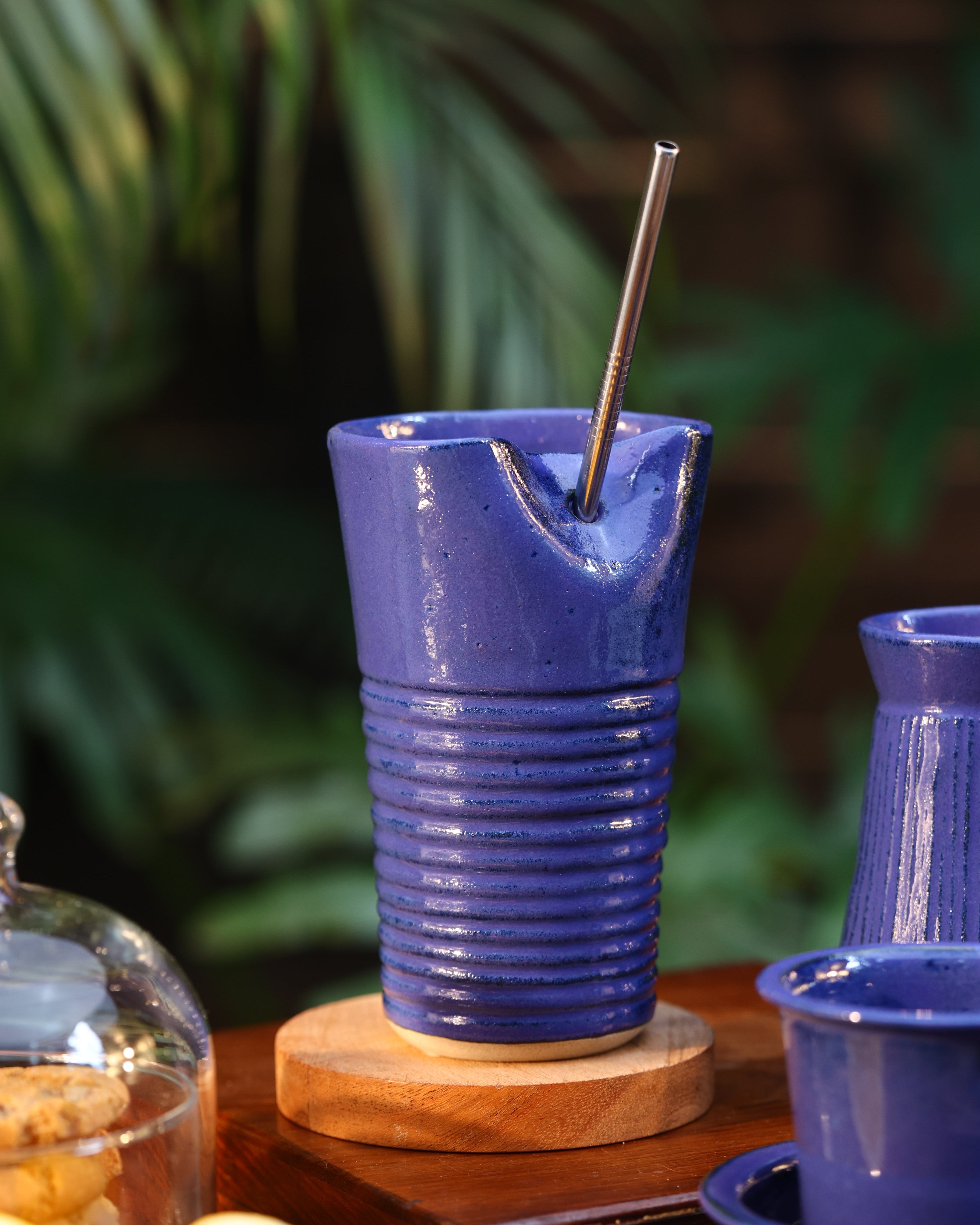 Close-up of a blue tumbler with a metal straw, ceramic coffee mugs online, Indian pottery brands online