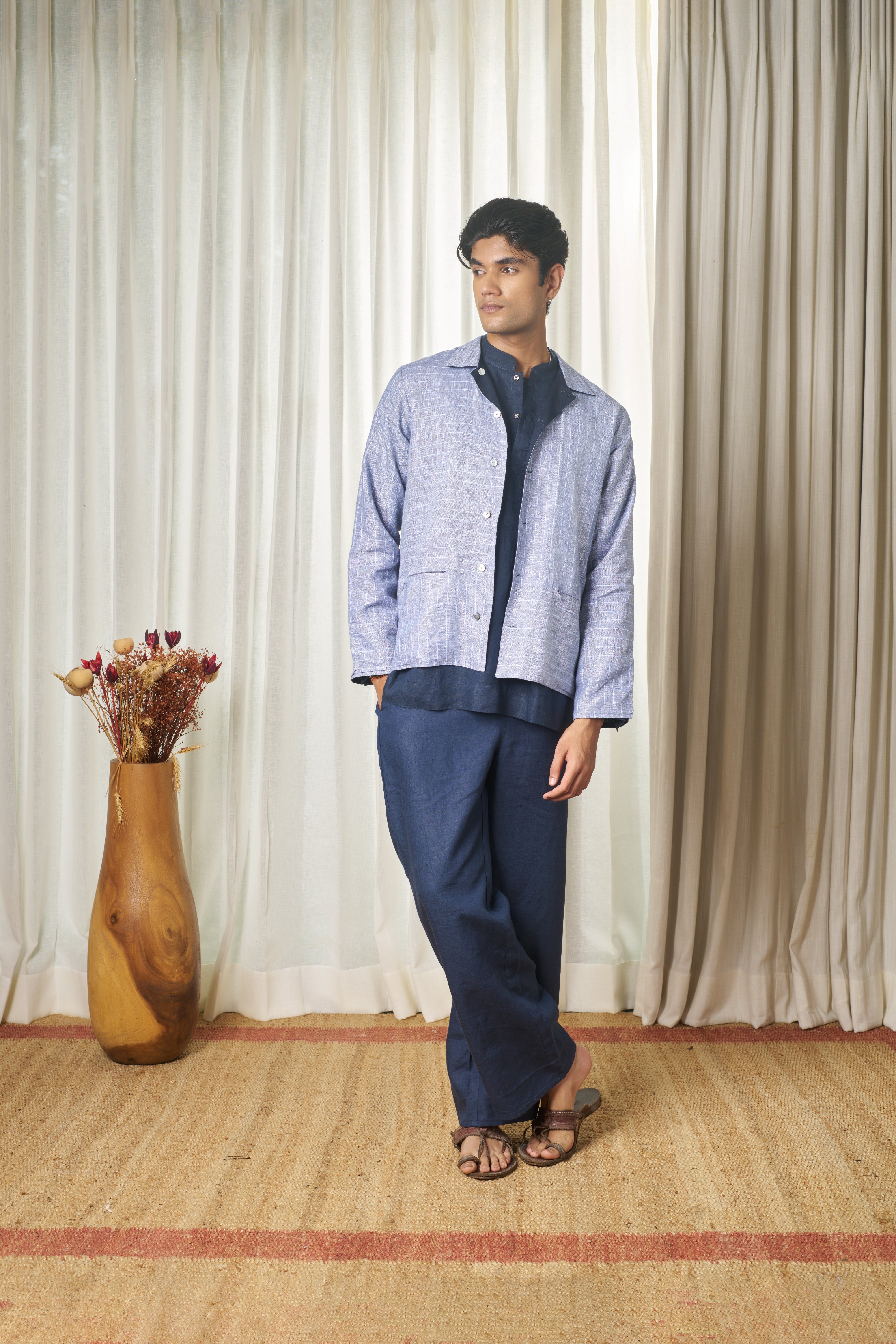 Person wearing a light blue striped shirt and dark pants. minimal menswear brands India, linen shirts for men India