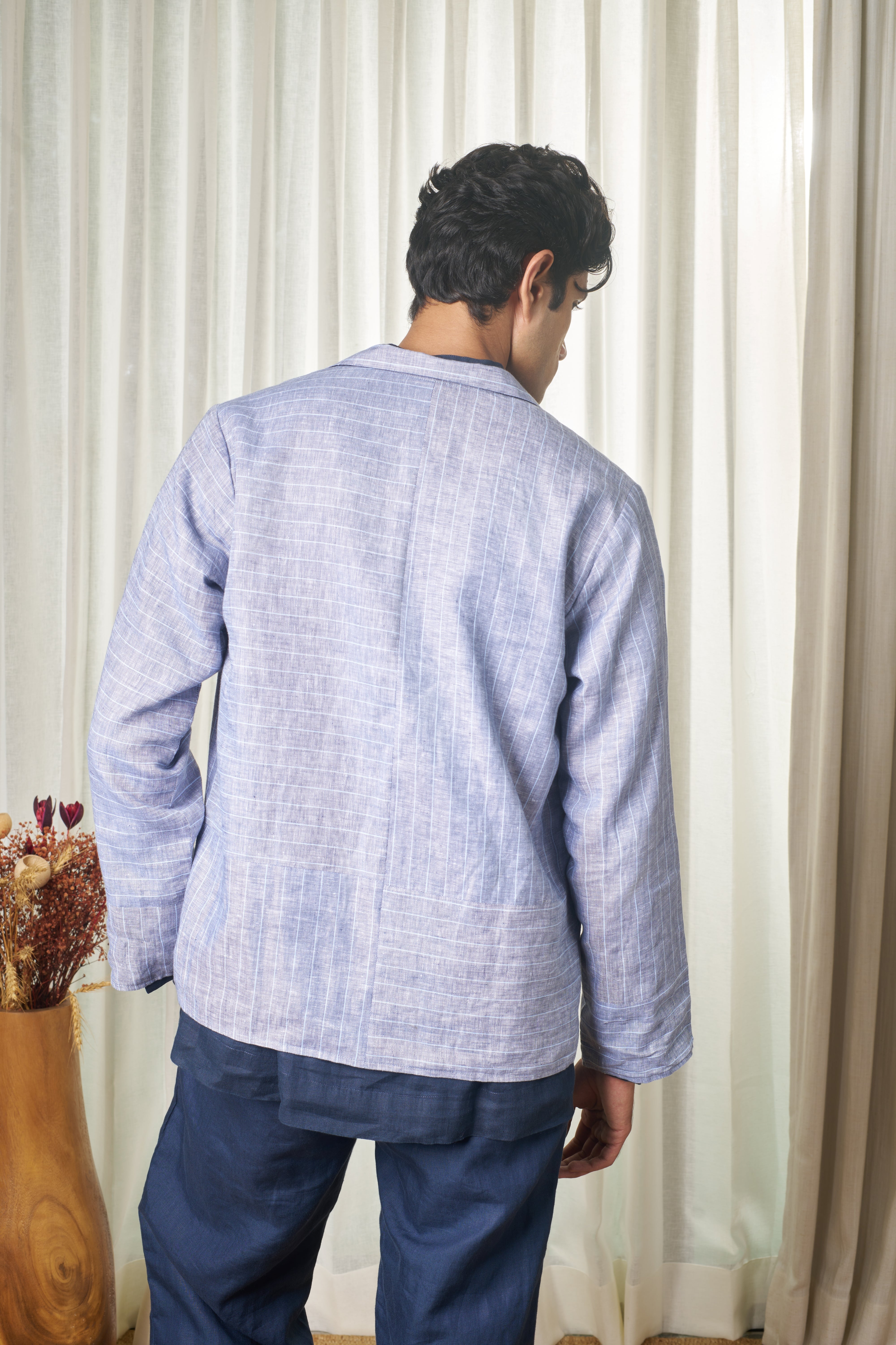 Person wearing a light blue striped shirt and dark pants. minimal menswear brands India, linen shirts for men India