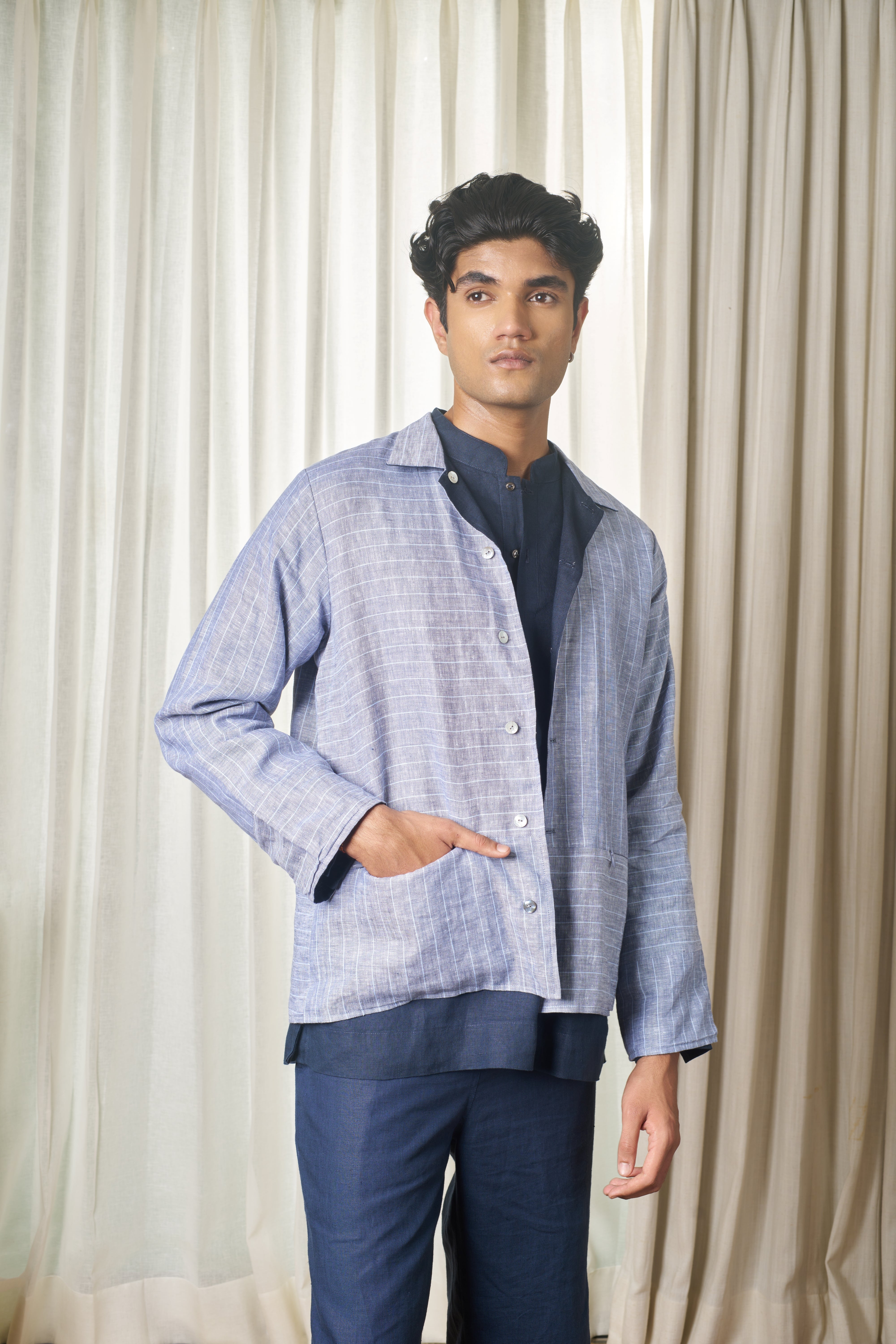 Person wearing a light blue striped shirt and dark pants.minimal menswear brands India, linen shirts for men India