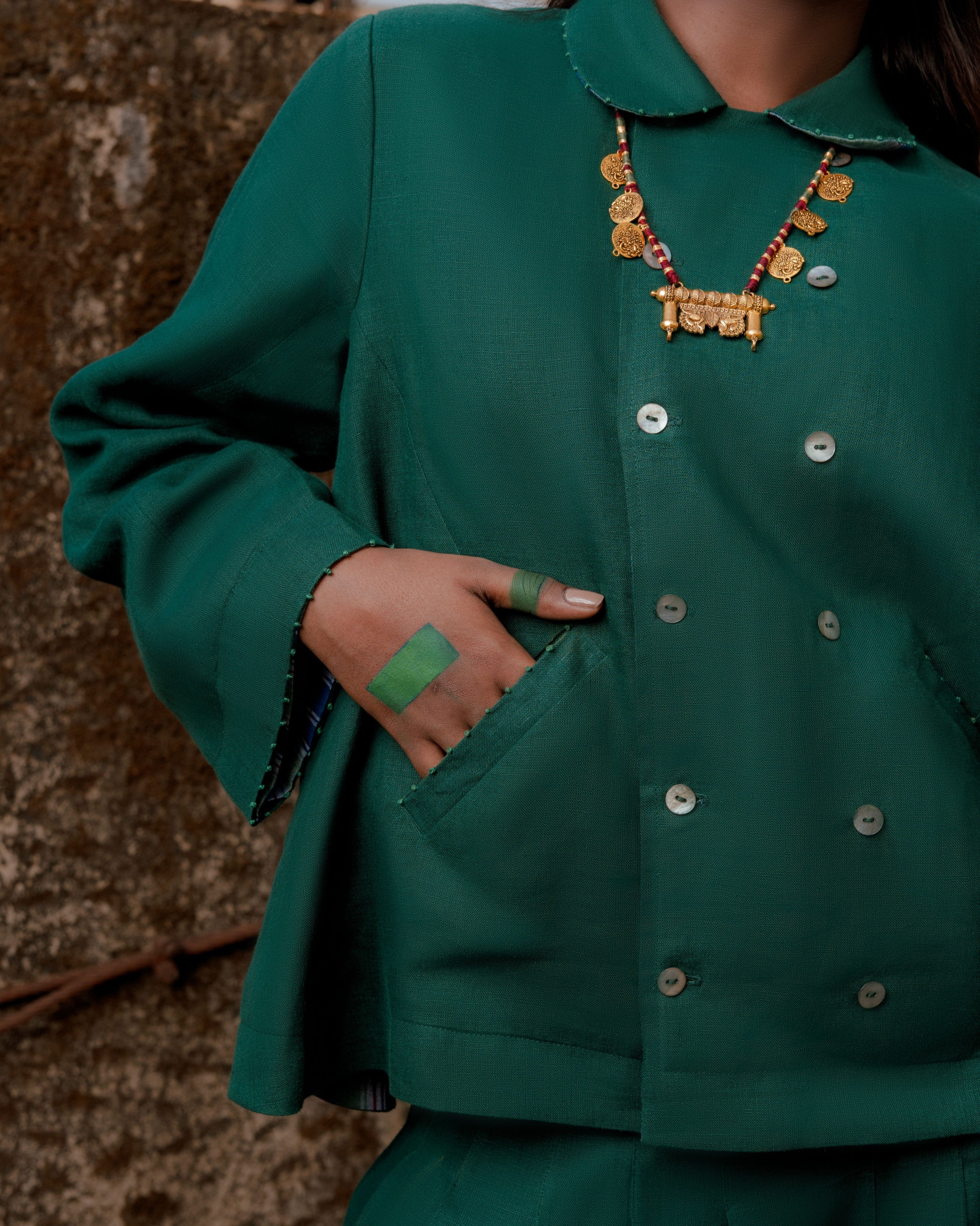 Person wearing a green outfit with a decorative necklace,  ethical clothing brands for women,
 minimalist clothing brands India
