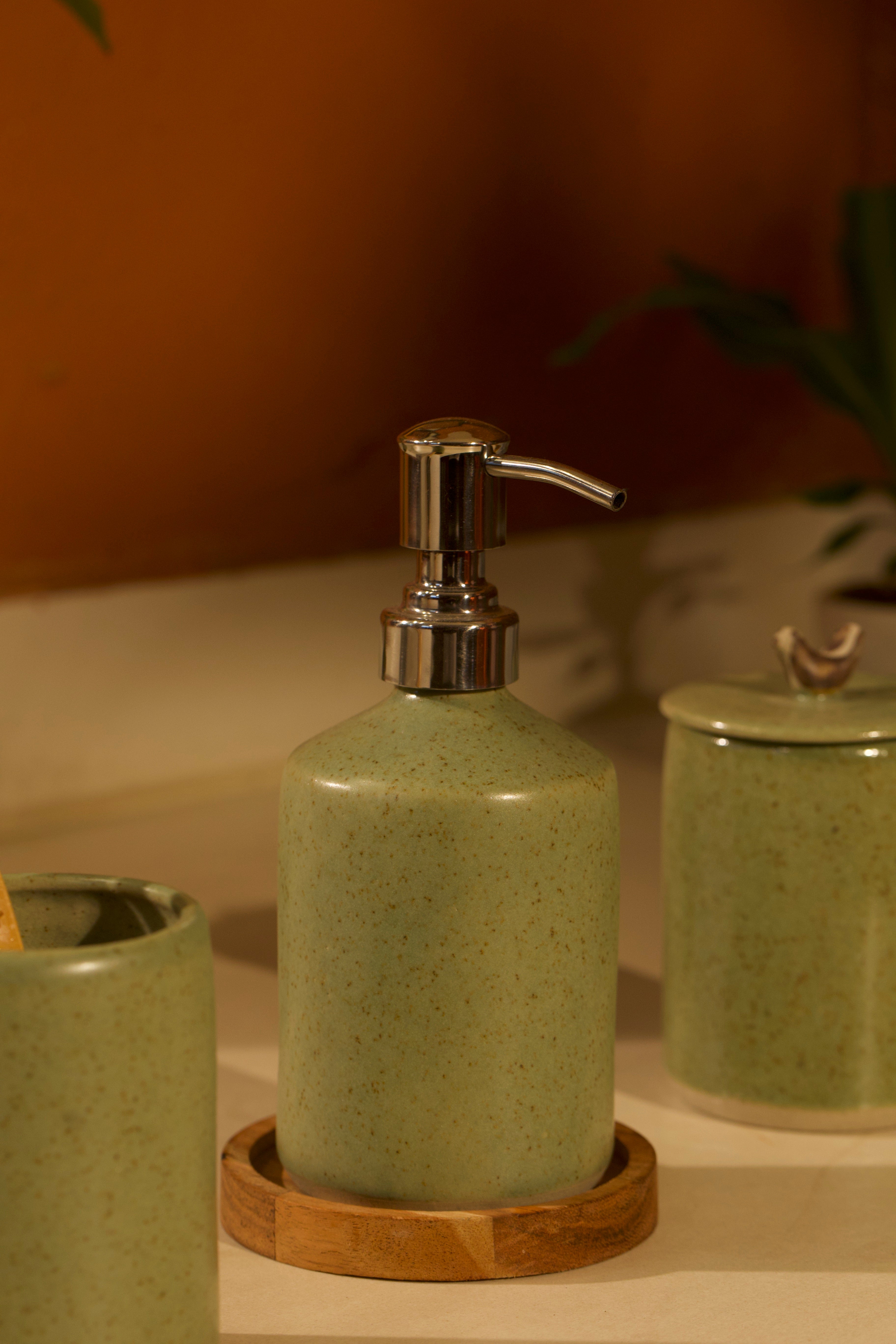 A green ceramic soap dispenser with pump on a wooden tray,  ceramic home décor online, pottery home decor
