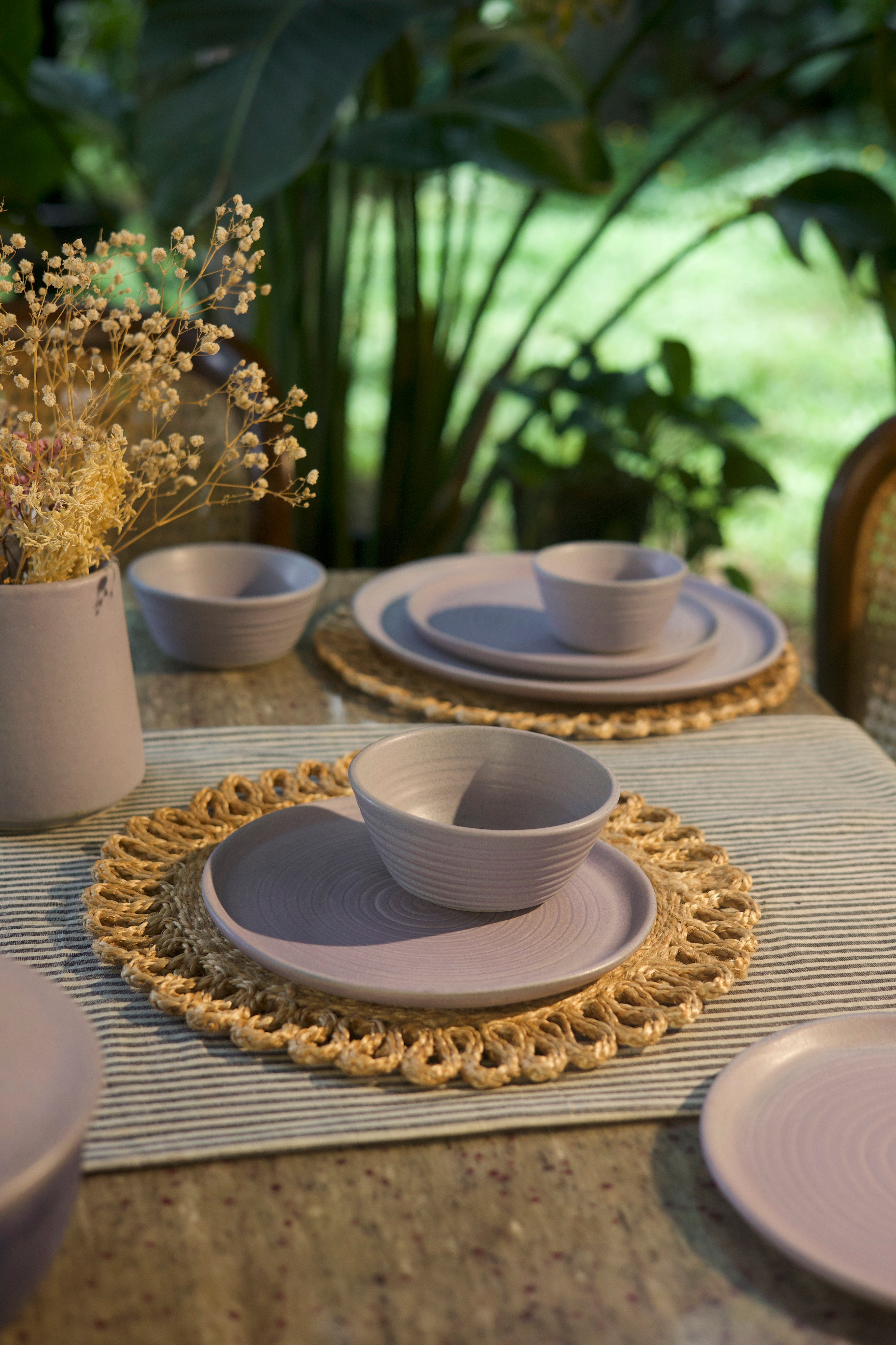 Lavendar ceramic plates and bowls on a textured surface handmade dinnerware India, handcrafted plates and bowls