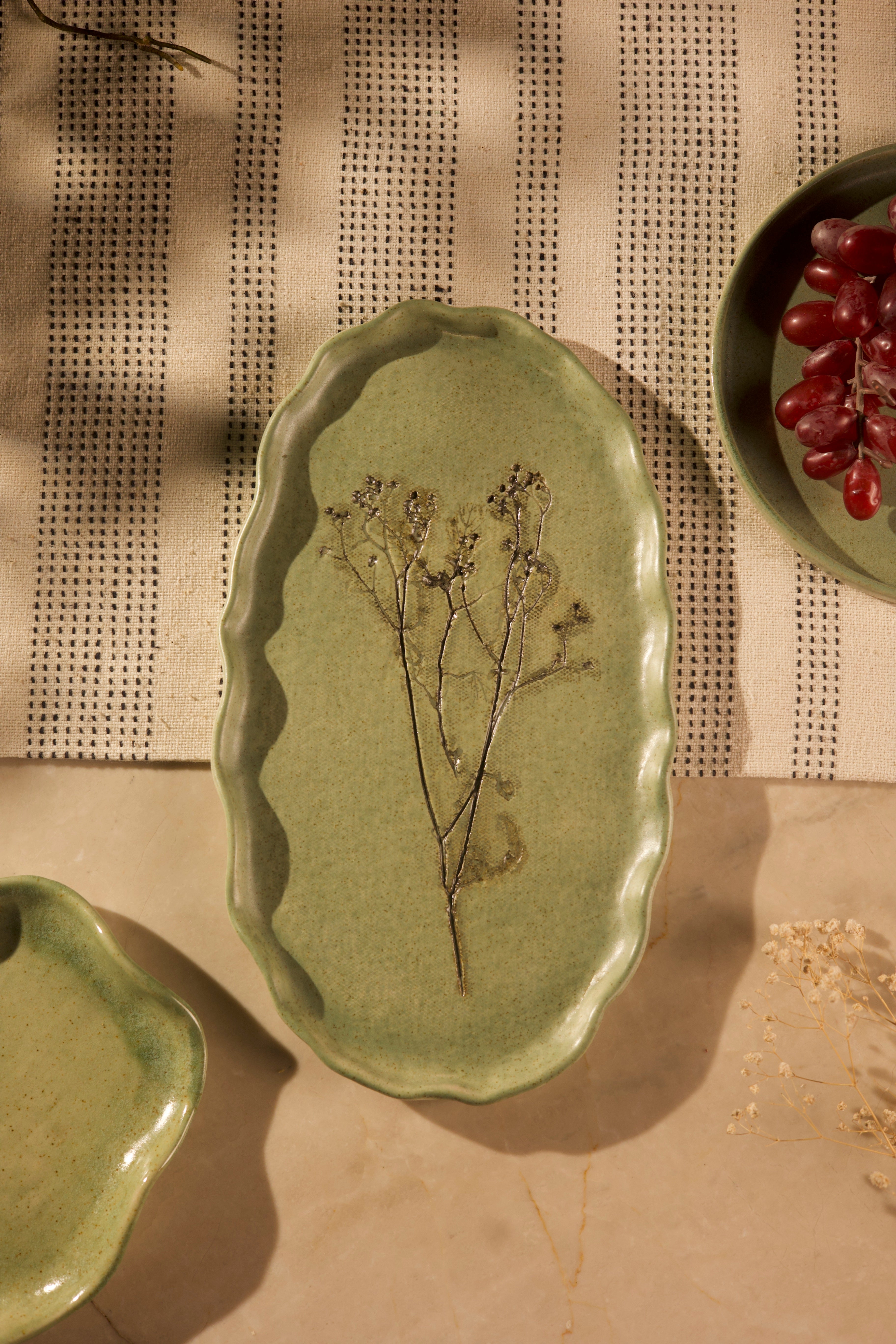 A green ceramic dish with pressed flowers on a textured surface handcrafted plates and bowls,
 dinner plates with natural glaze