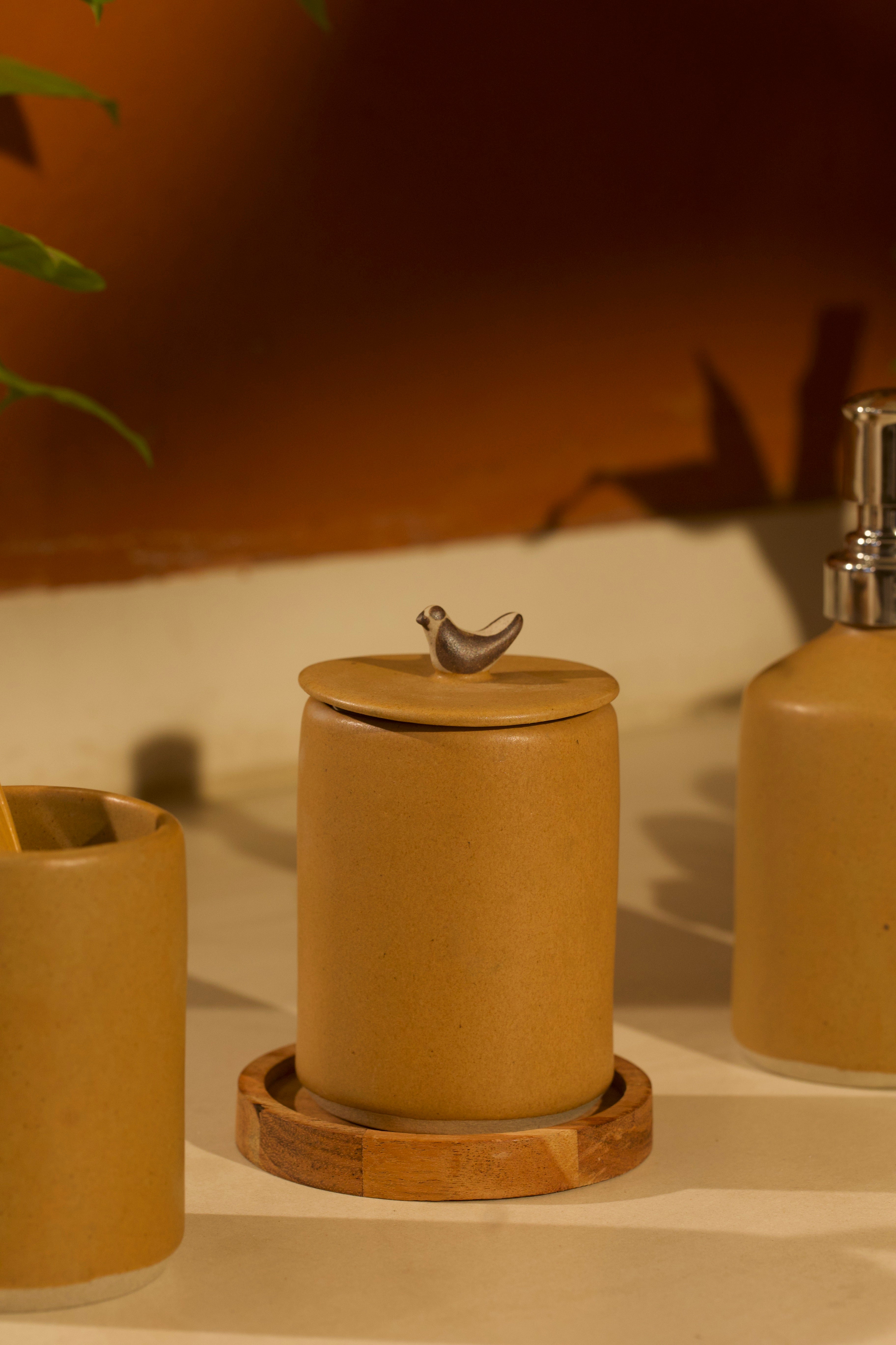 Set of ceramic containers with a bird figurine on top, placed on a wooden coaster.  ceramic home décor online, pottery home decor