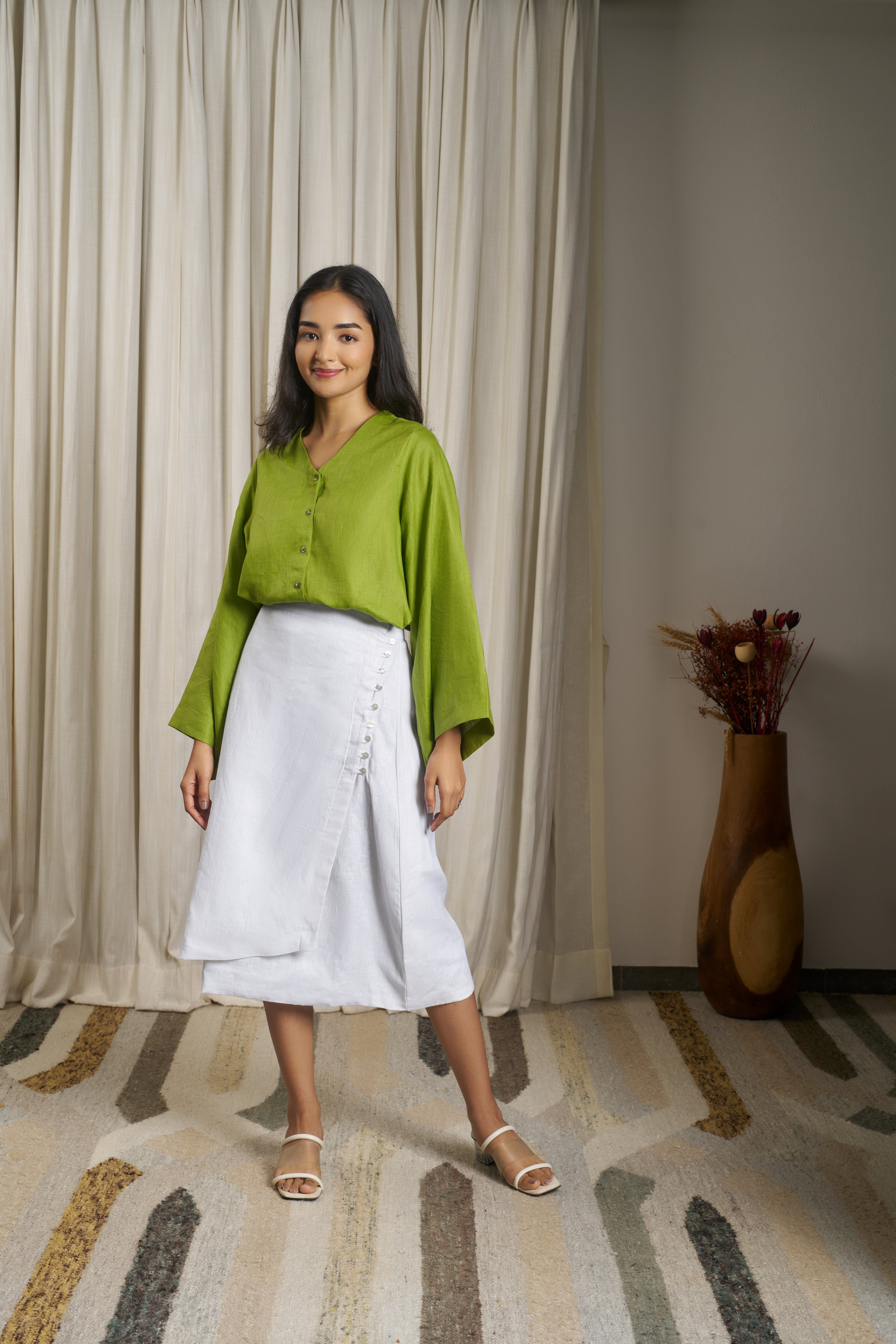 Woman wearing a green blouse and white skirt.