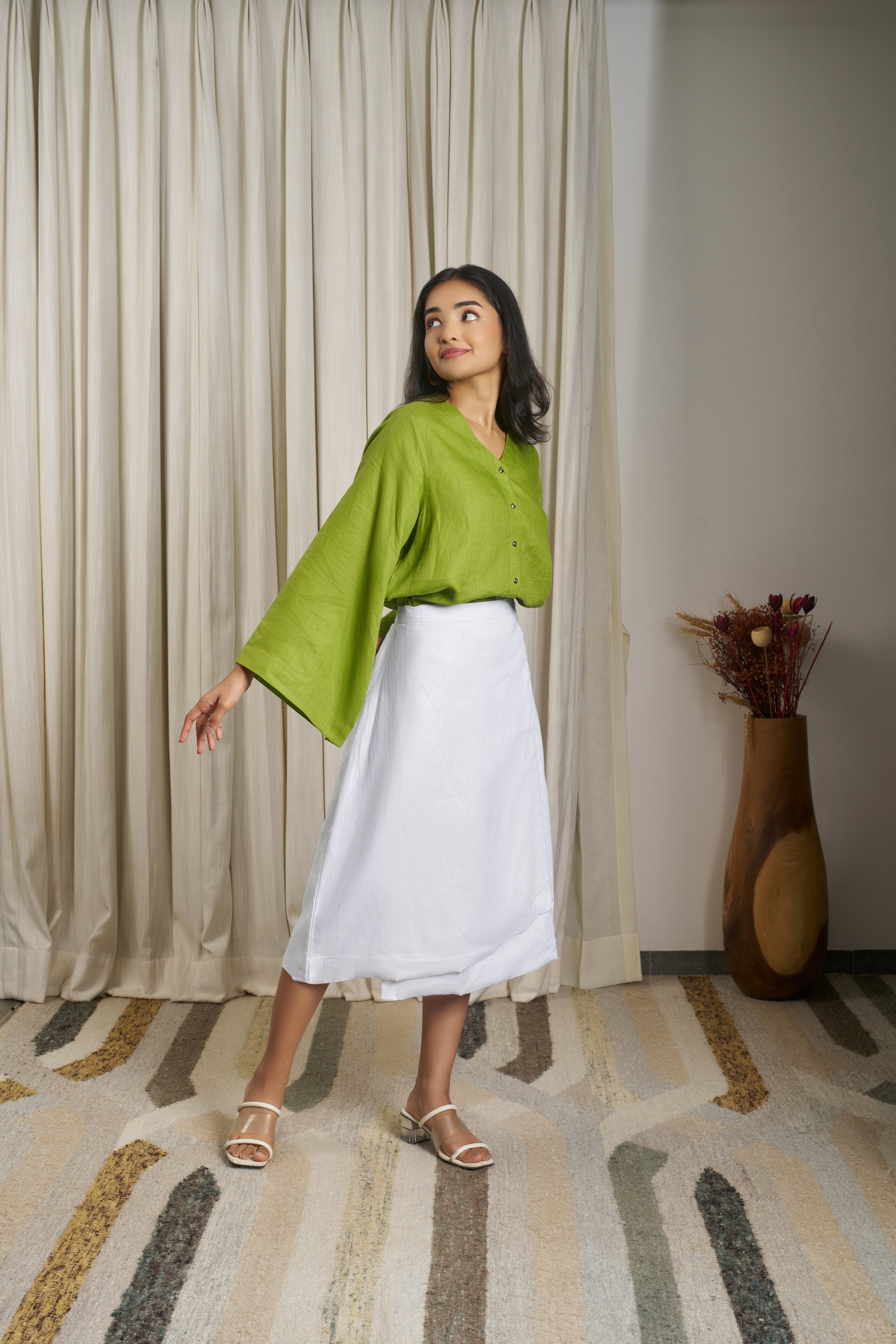 Woman wearing a green blouse and white skirt.