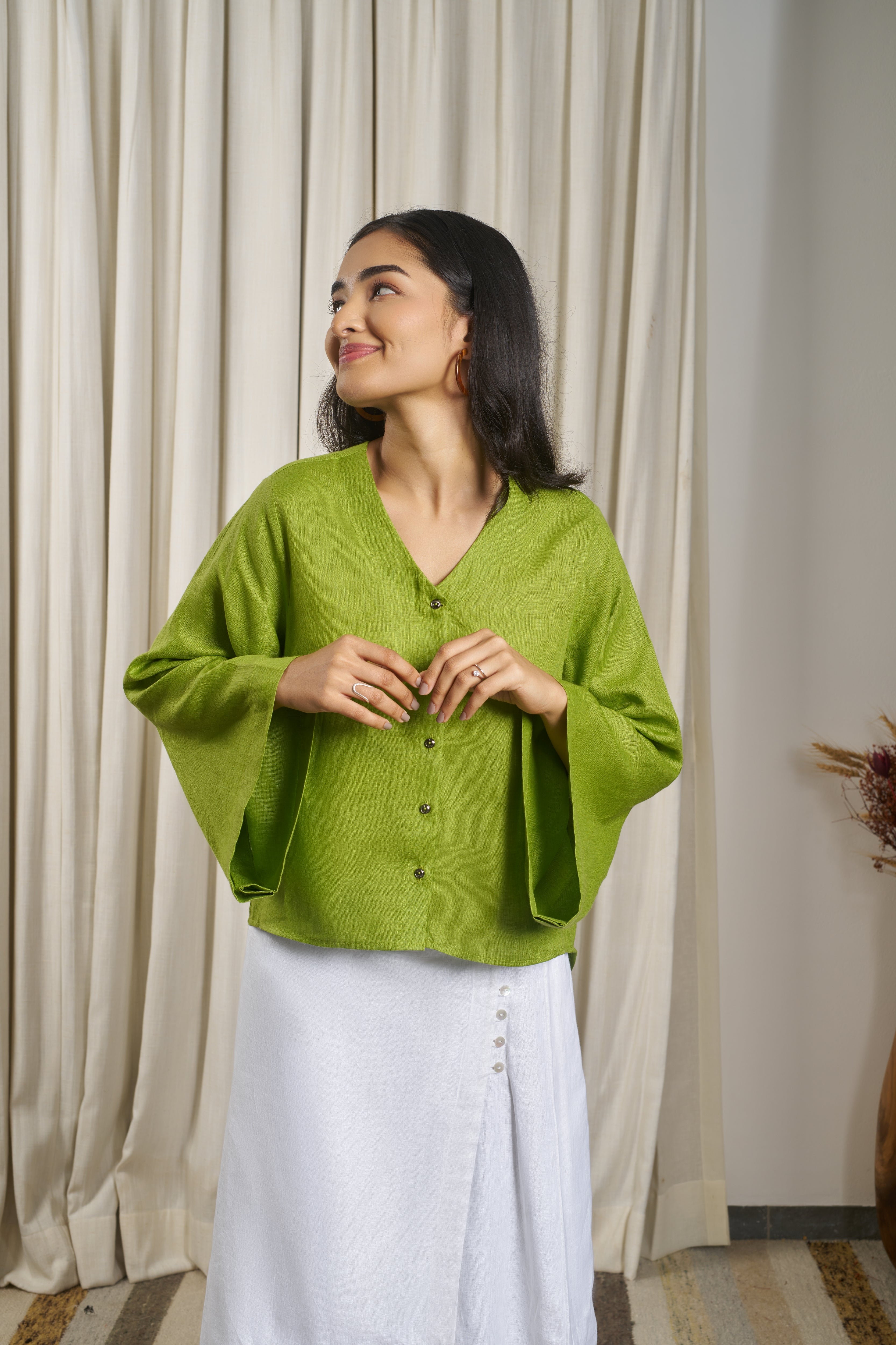 Woman wearing a green blouse and white skirt.