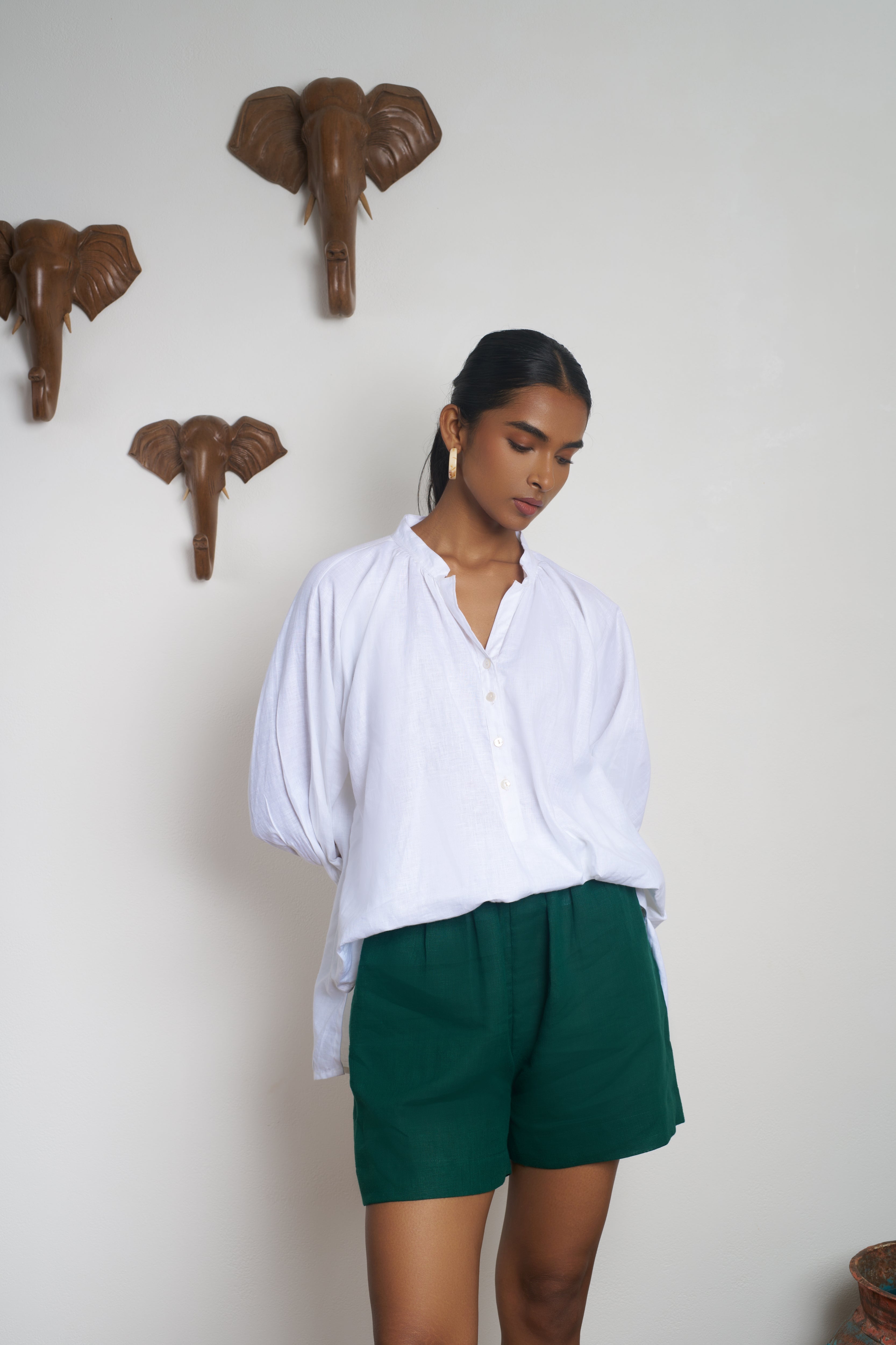 Woman wearing a white shirt and green shorts.  everyday sustainable fashion India,  timeless women’s fashion
