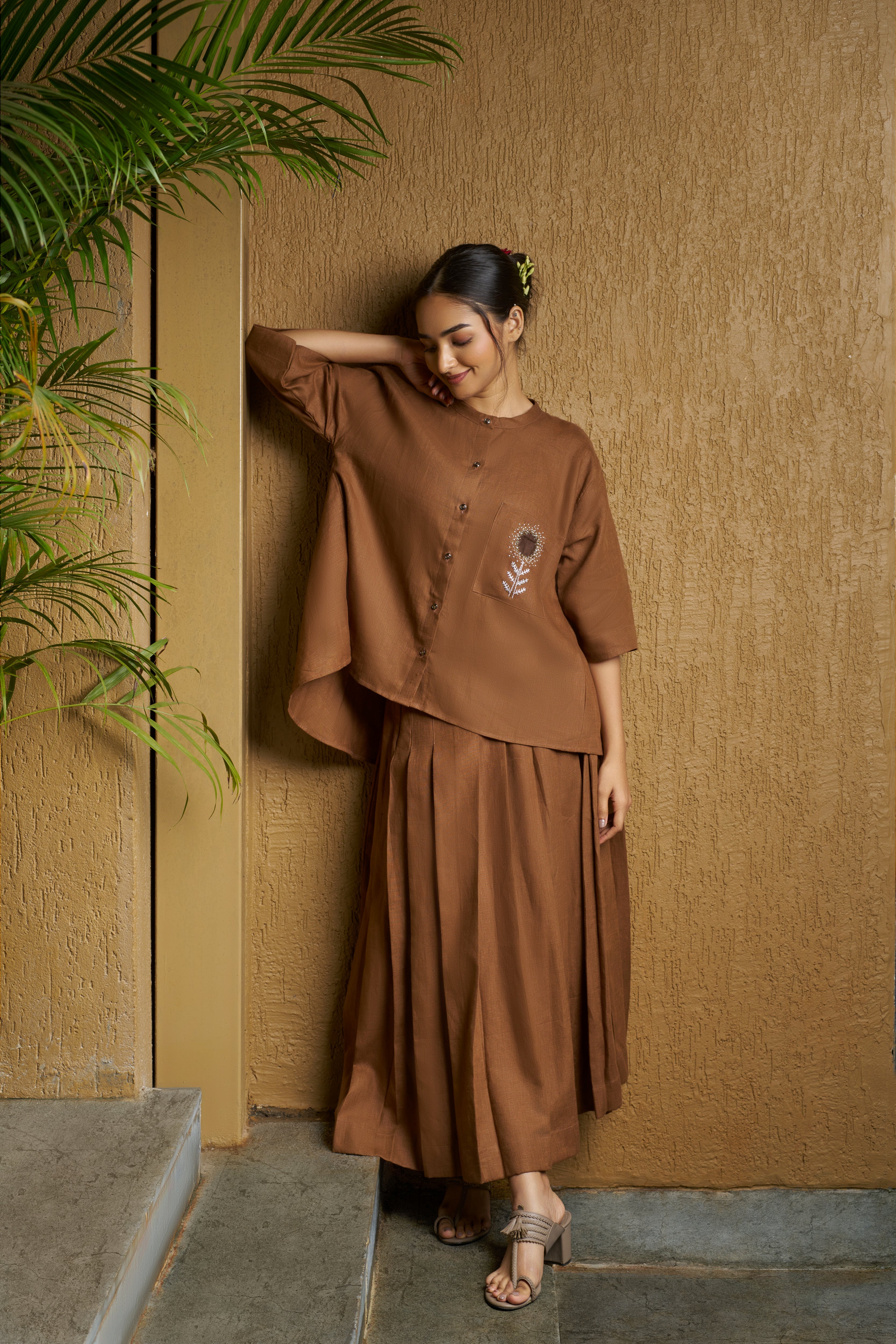 Woman in a brown blouse with embroidered white flower and brown skirt. timeless women’s fashion, 100% linen clothes India
