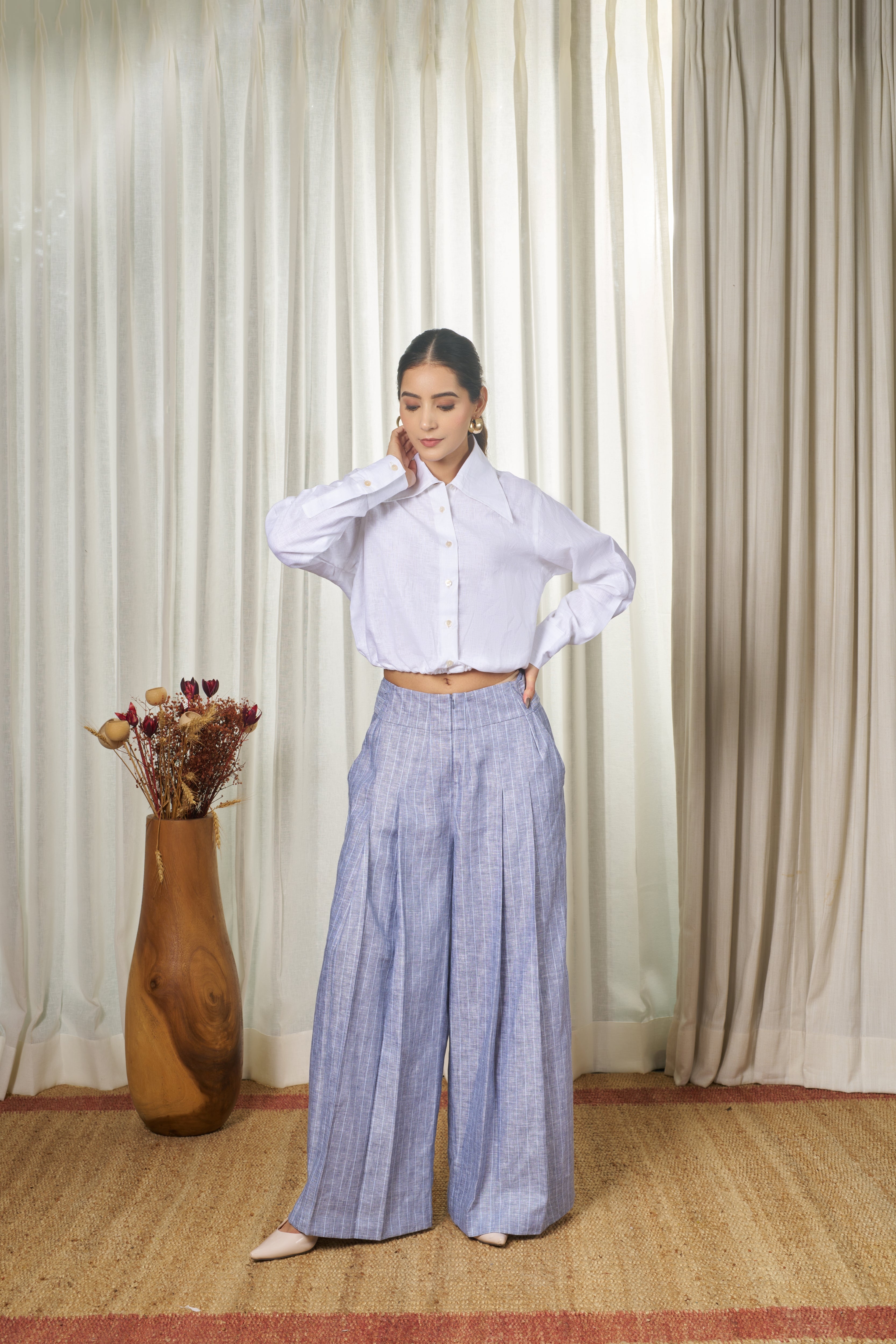 Woman wearing a white shirt and blue pants with strips. Casual linen fashion,  
timeless women’s fashion