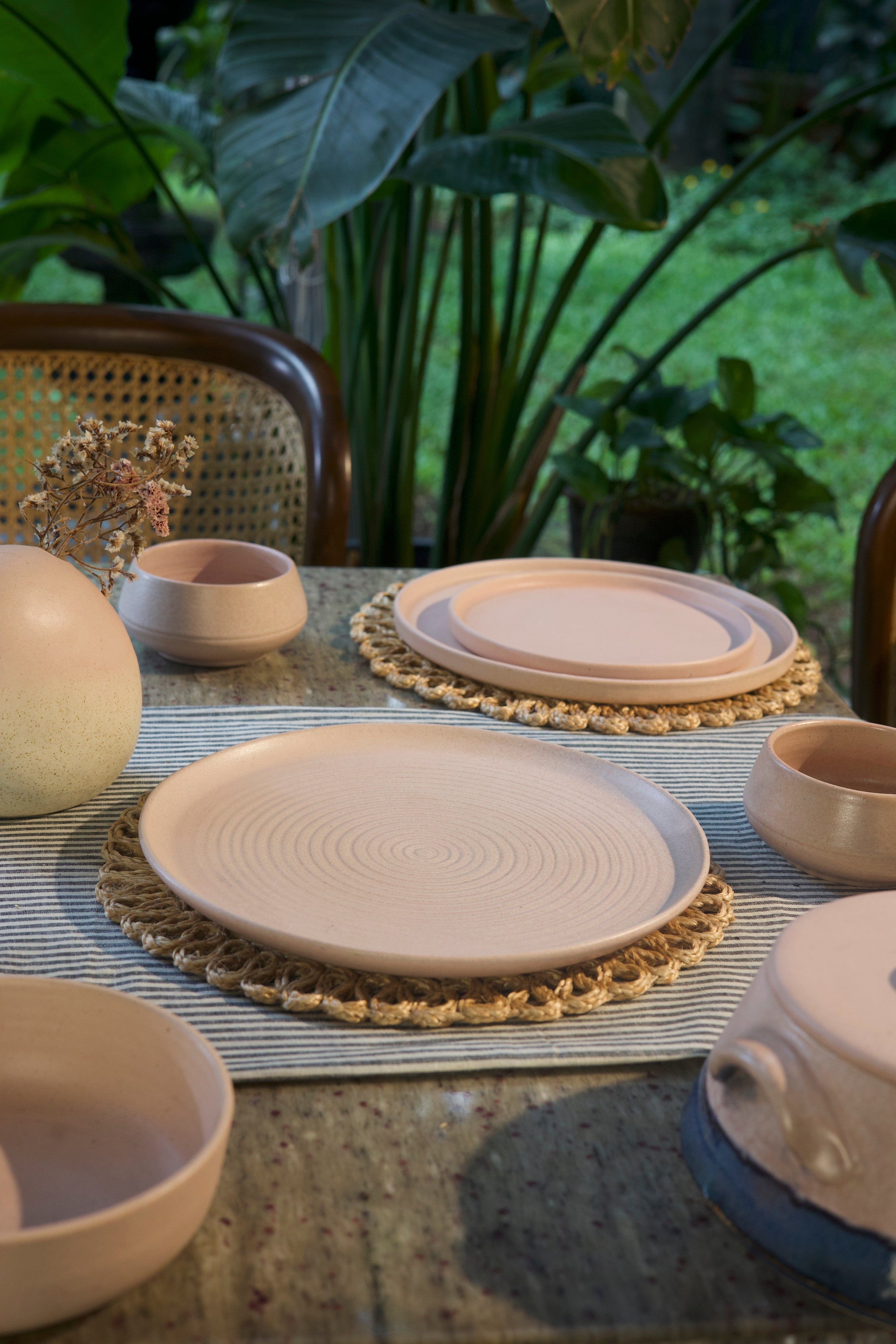 Pink ceramic plates and bowls on a table with a natural background  handmade dinnerware India, handcrafted plates and bowls