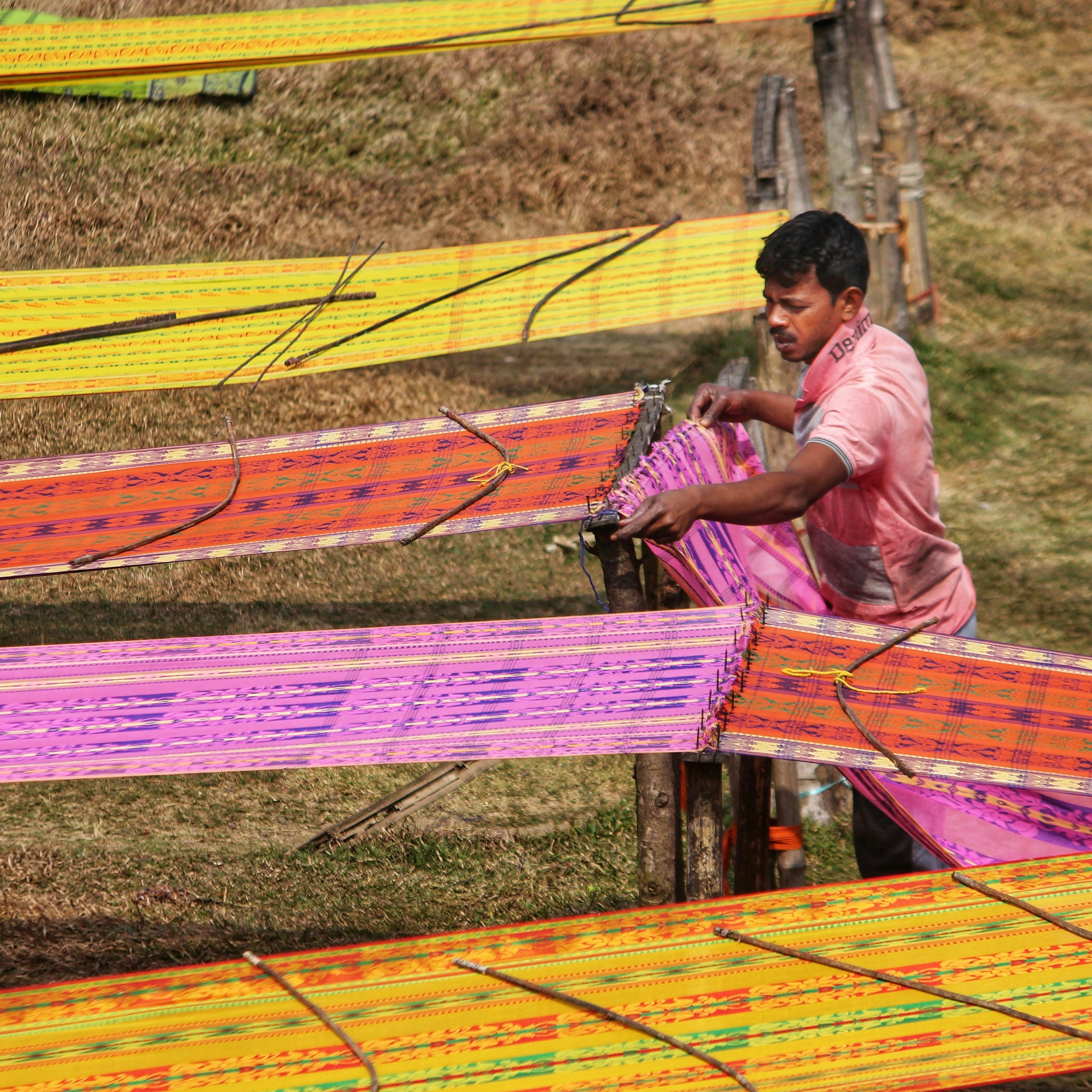 Person working with colorful fabric on a traditional loom outdoors,  natural dye clothing India, zero waste lifestyle brands