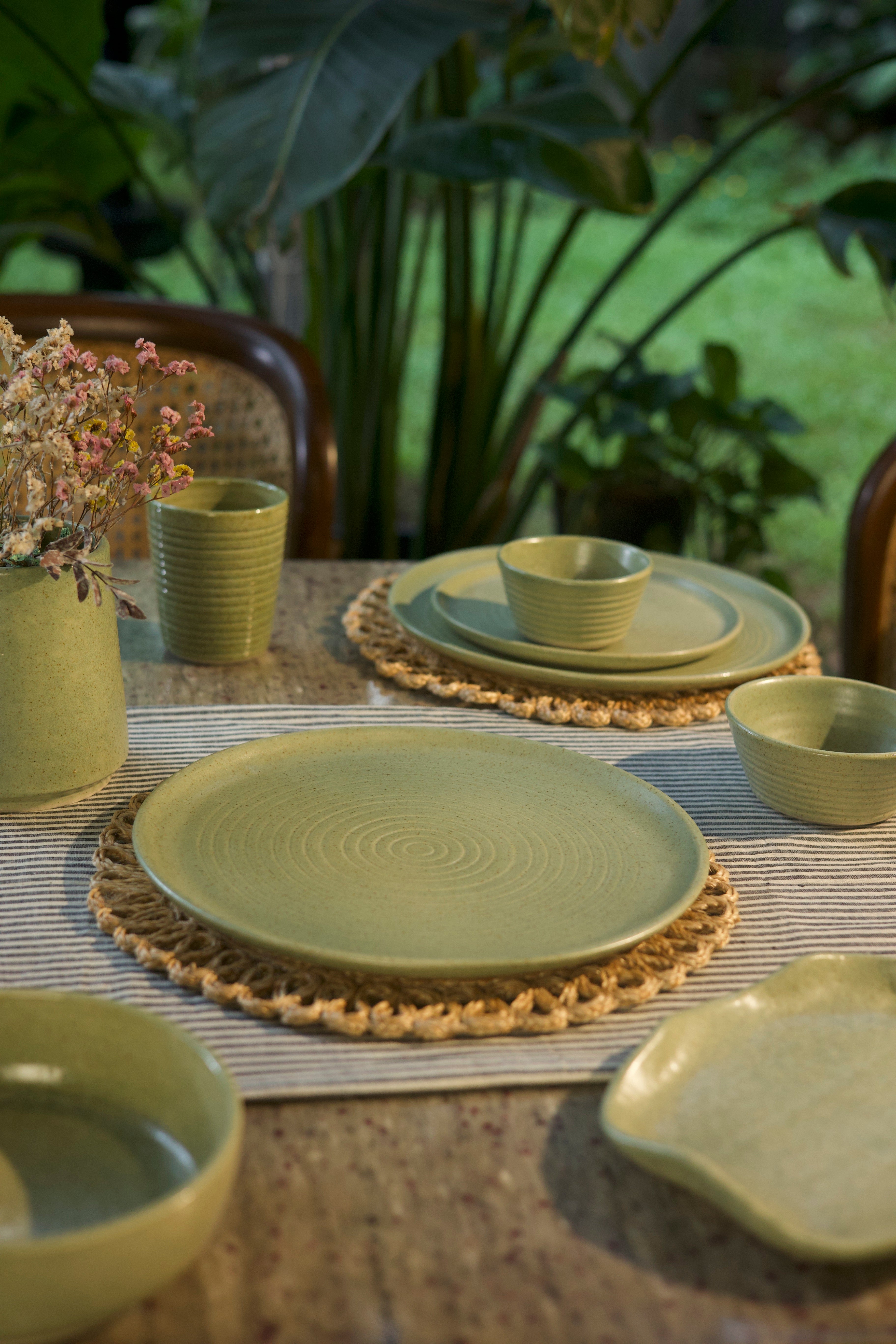 Green ceramic tableware set on a textured surface  handmade dinnerware India, handcrafted plates and bowls