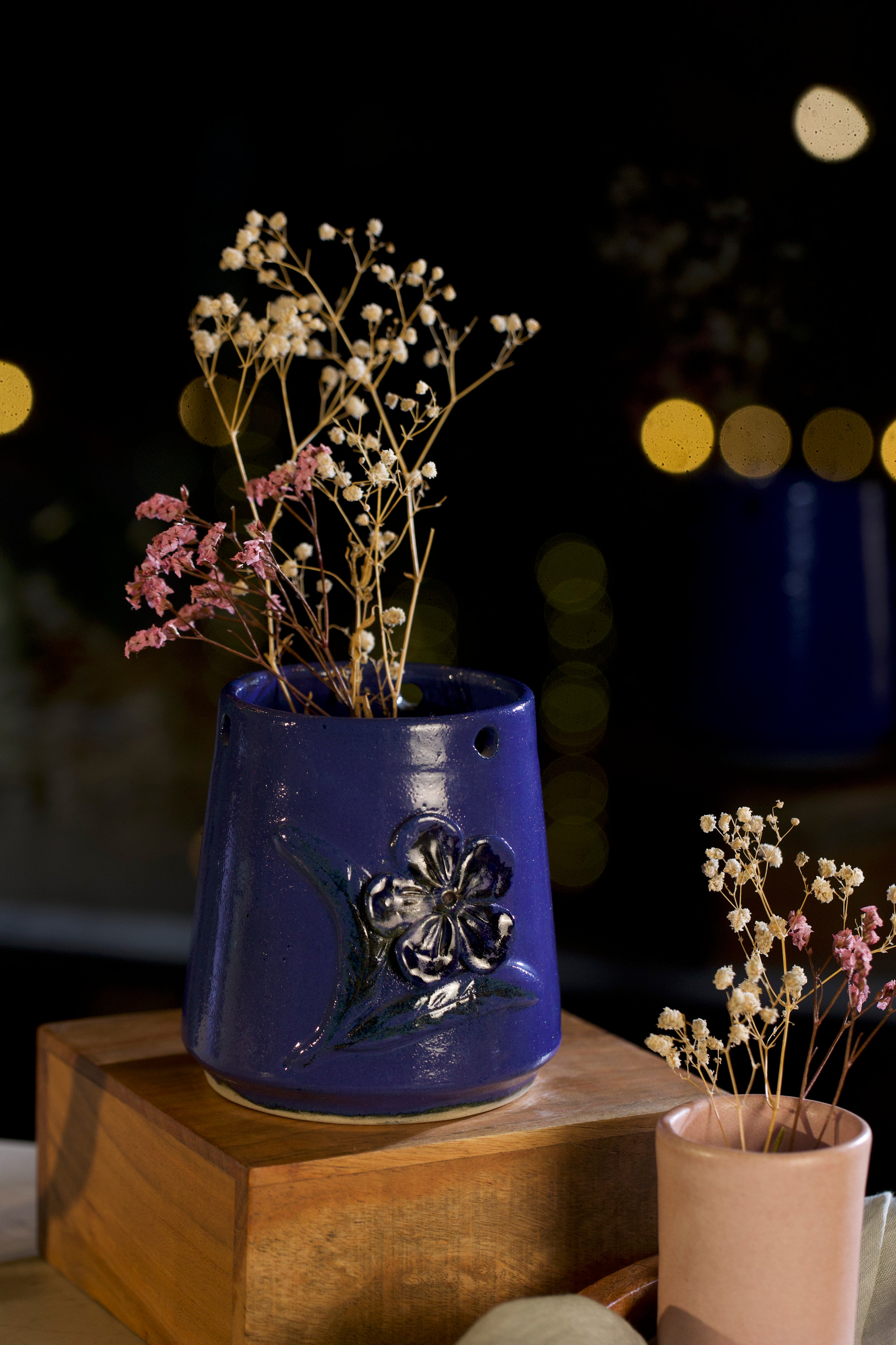 Blue ceramic vase with floral design containing dried flowers on a wooden surface.  pottery home decor,  
handmade clay planters