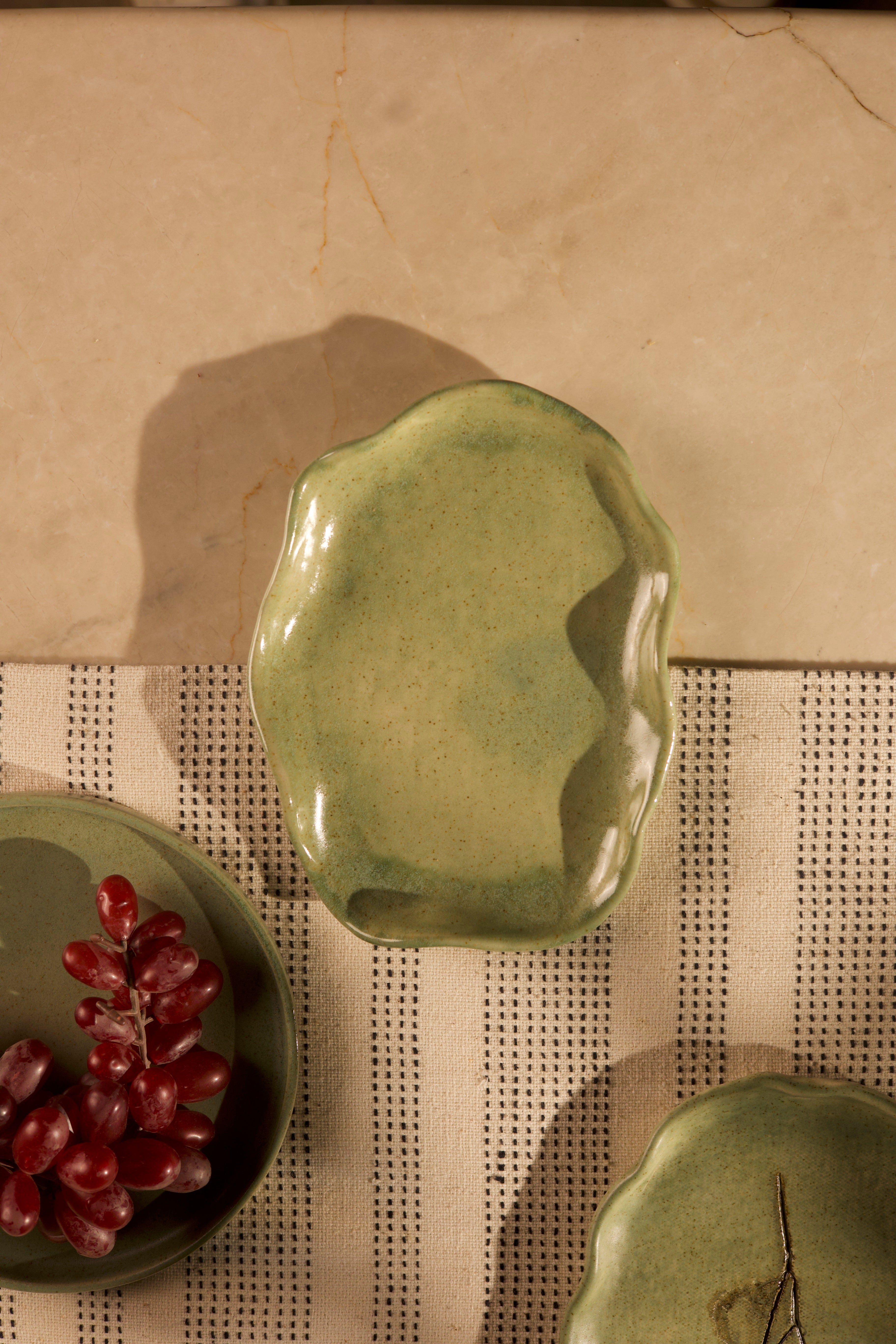 Green ceramic dish on a textured surface. handcrafted plates and bowls, dinner plates with natural glaze