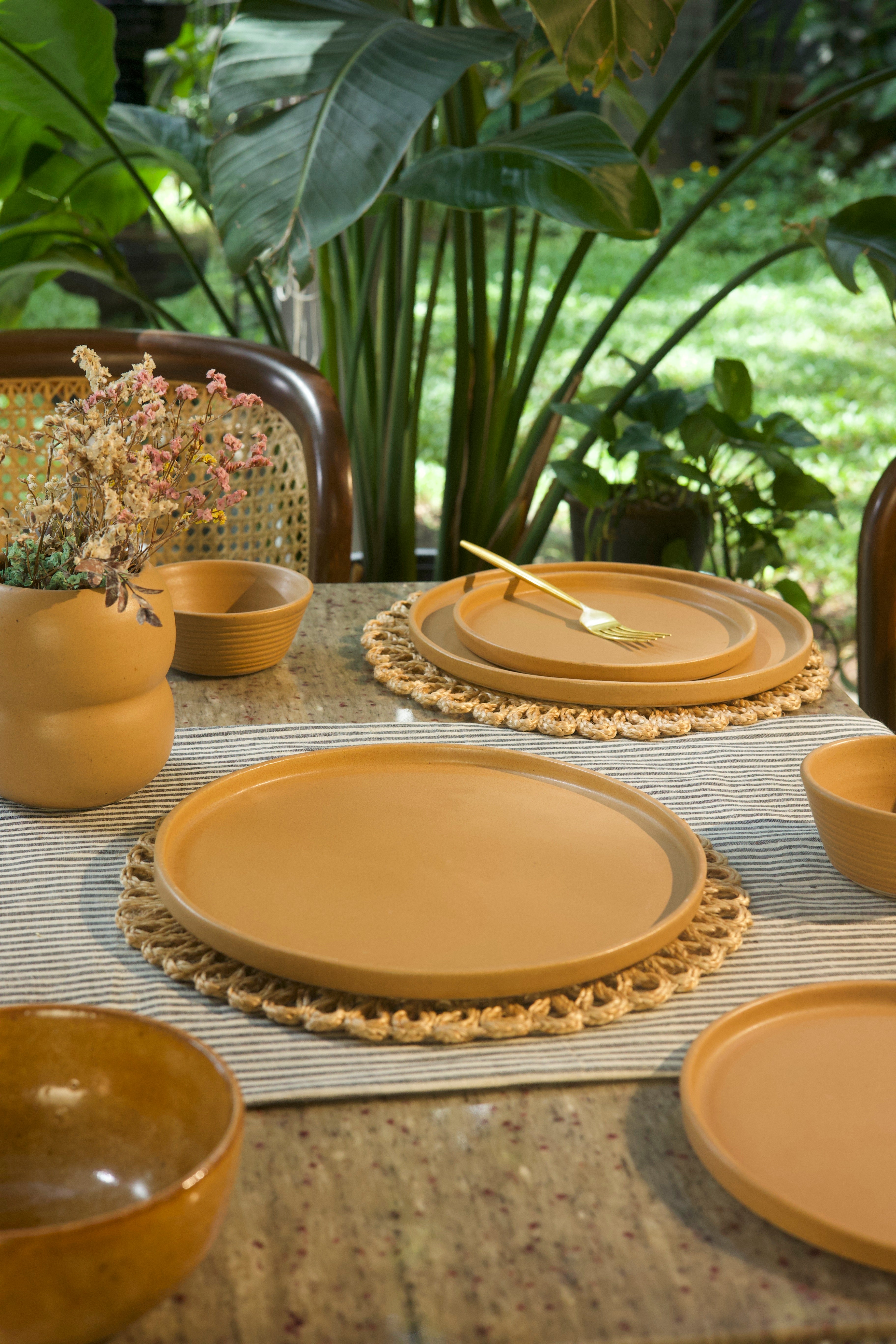 Dining table setting with ceramic plates and bowls on a textured surface , handmade dinnerware India, handcrafted plates and bowls