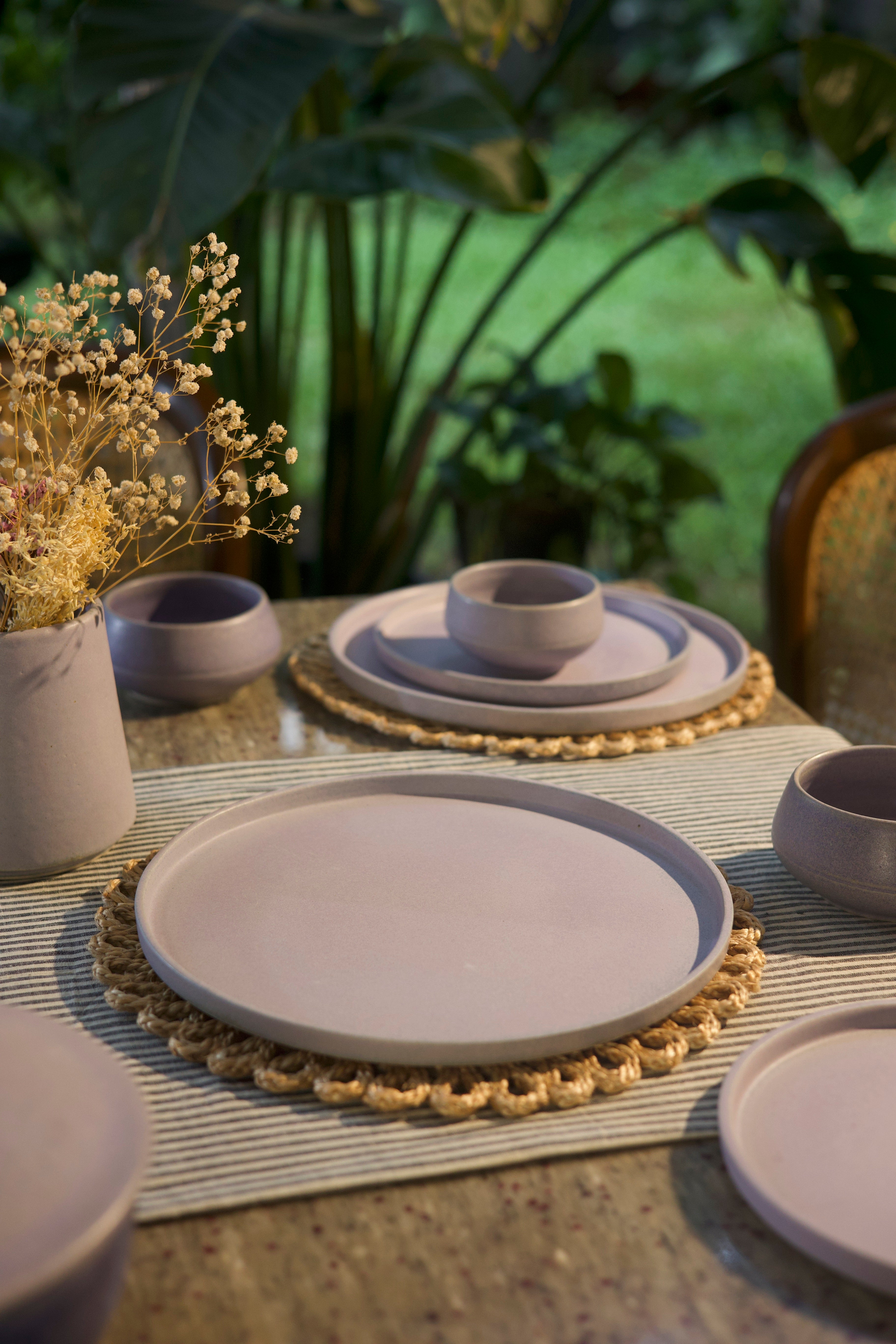 Pink ceramic plates and bowls on a table with a natural background, handmade dinnerware India, handcrafted plates and bowls