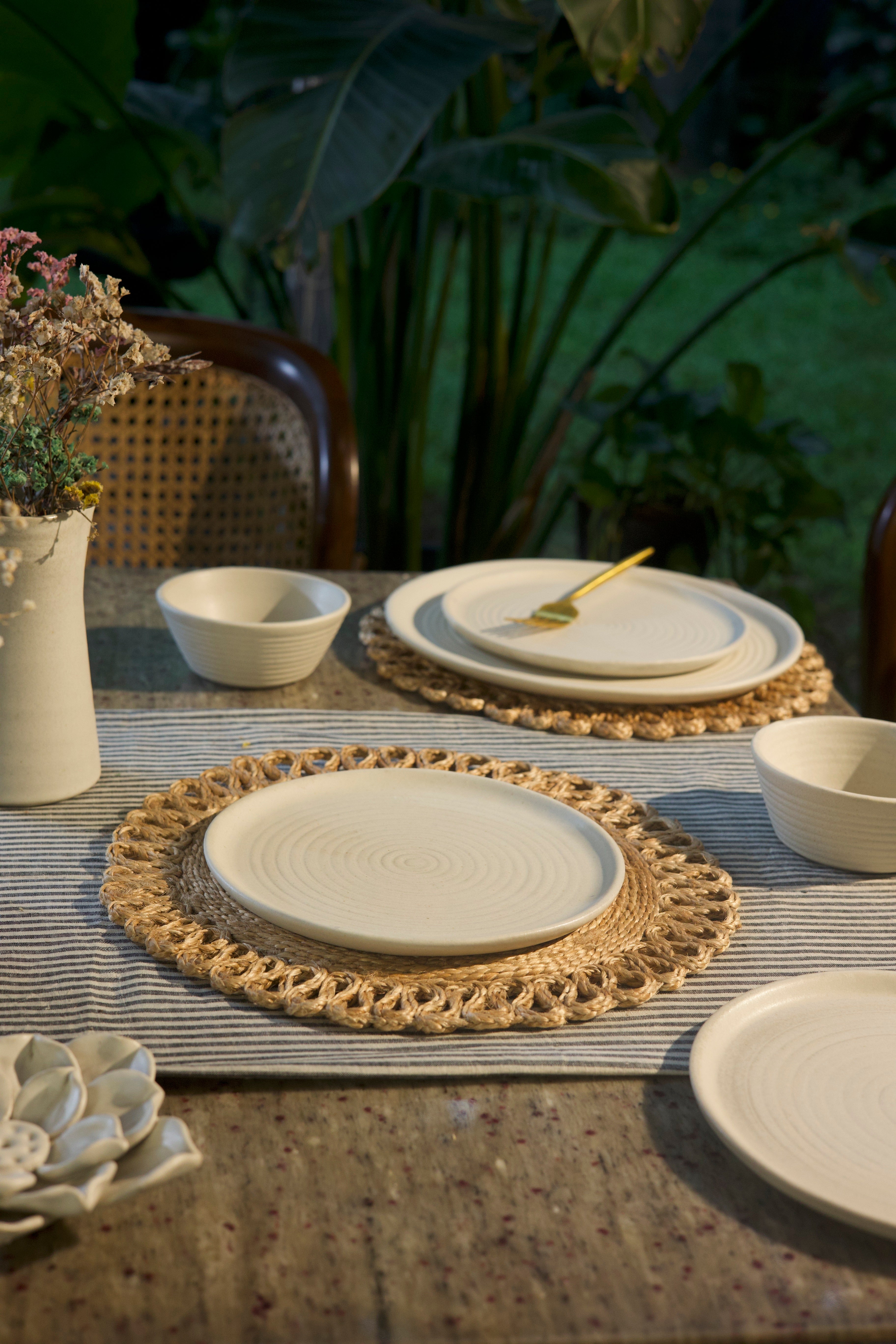 White dining table setting with ceramic plates, bowls, and a woven placemat,  handmade dinnerware India, handcrafted plates and bowls